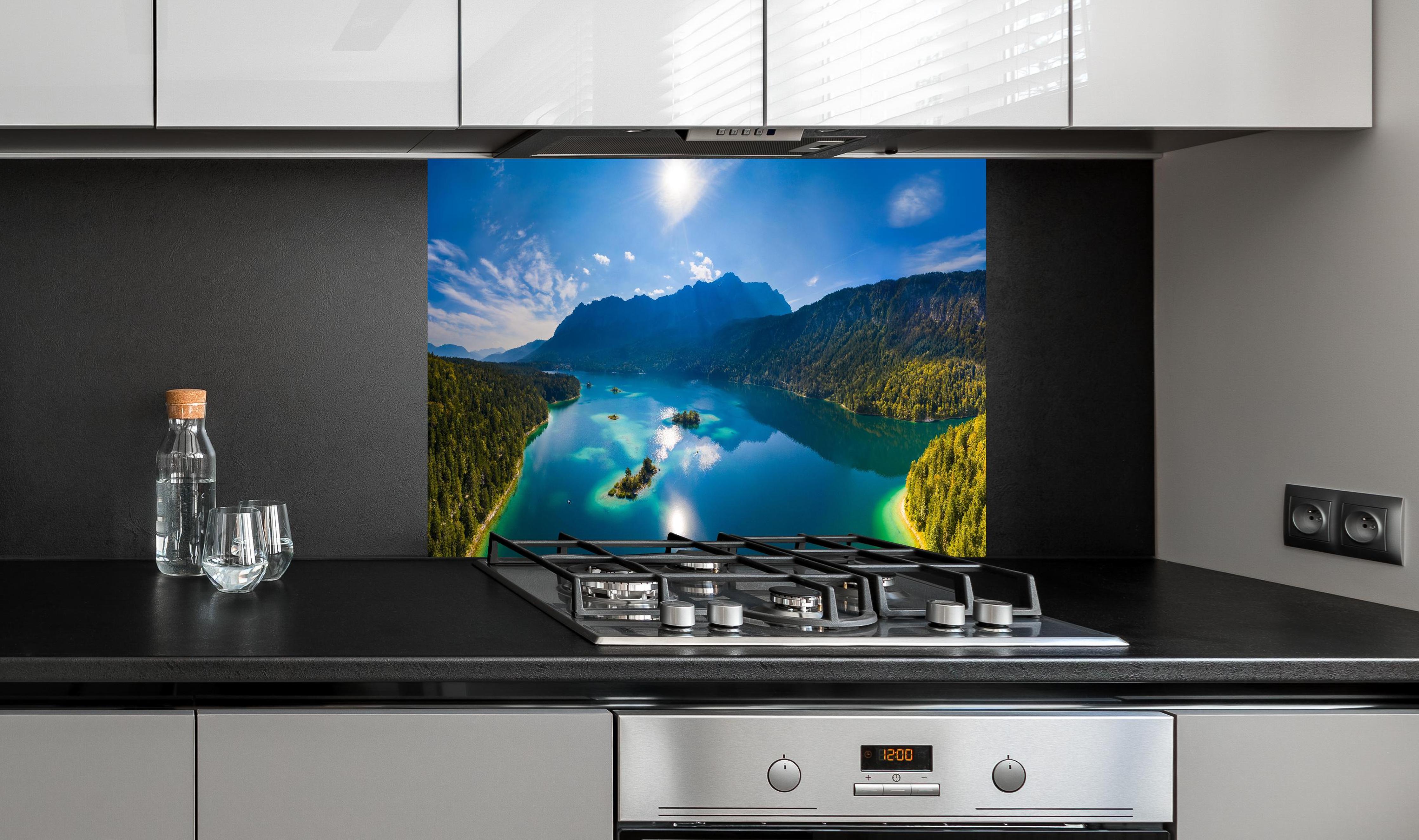 Spritzschutz - Eibsees mit der Zugspitze im Hintergrund hinter einem Cerankochfeld zwischen Holz-Kochutensilien
