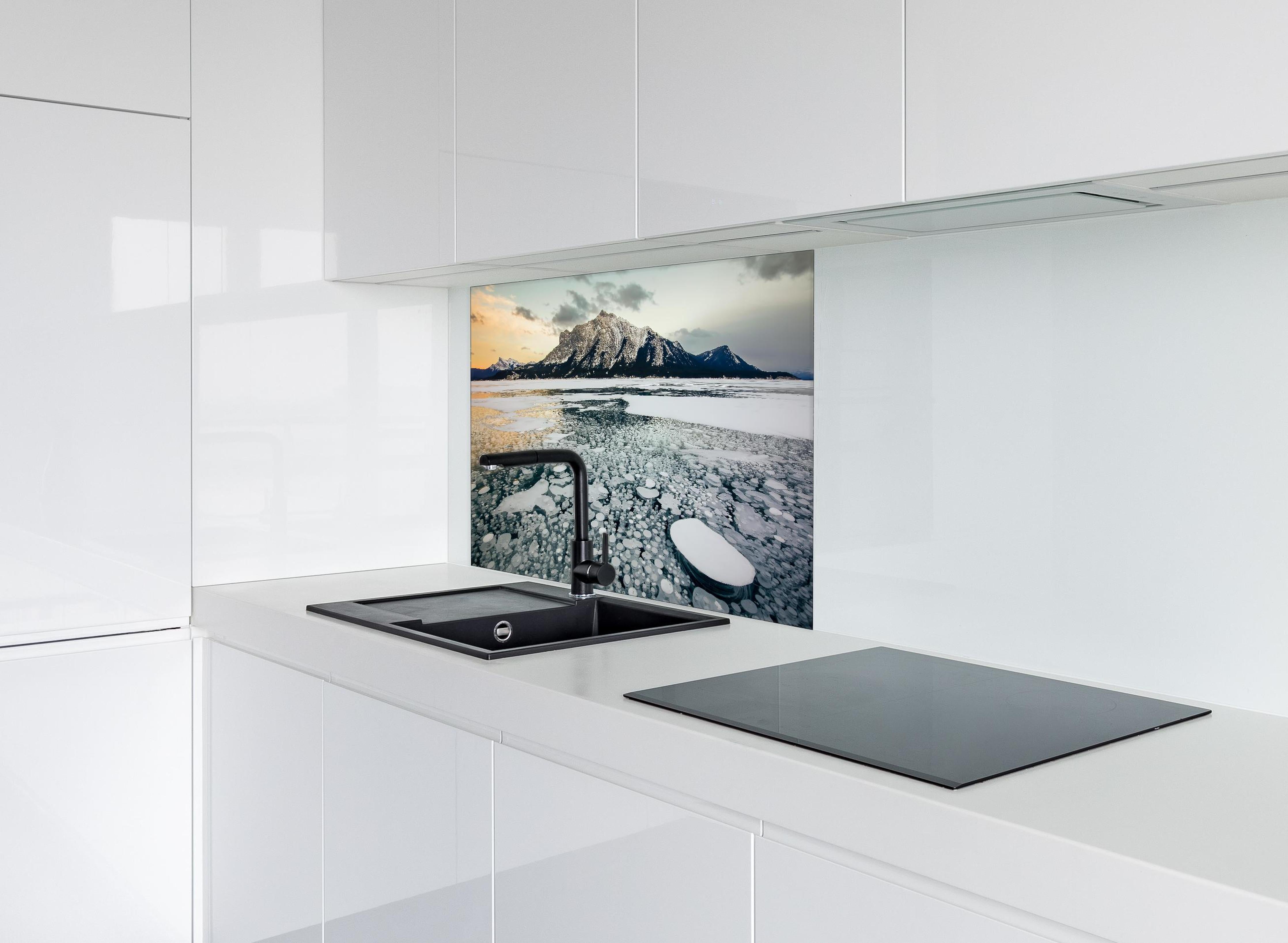 Spritzschutz - Eisblasen im gefrorenen Bergsee bei Sonnenuntergang hinter einem Cerankochfeld zwischen Holz-Kochutensilien
