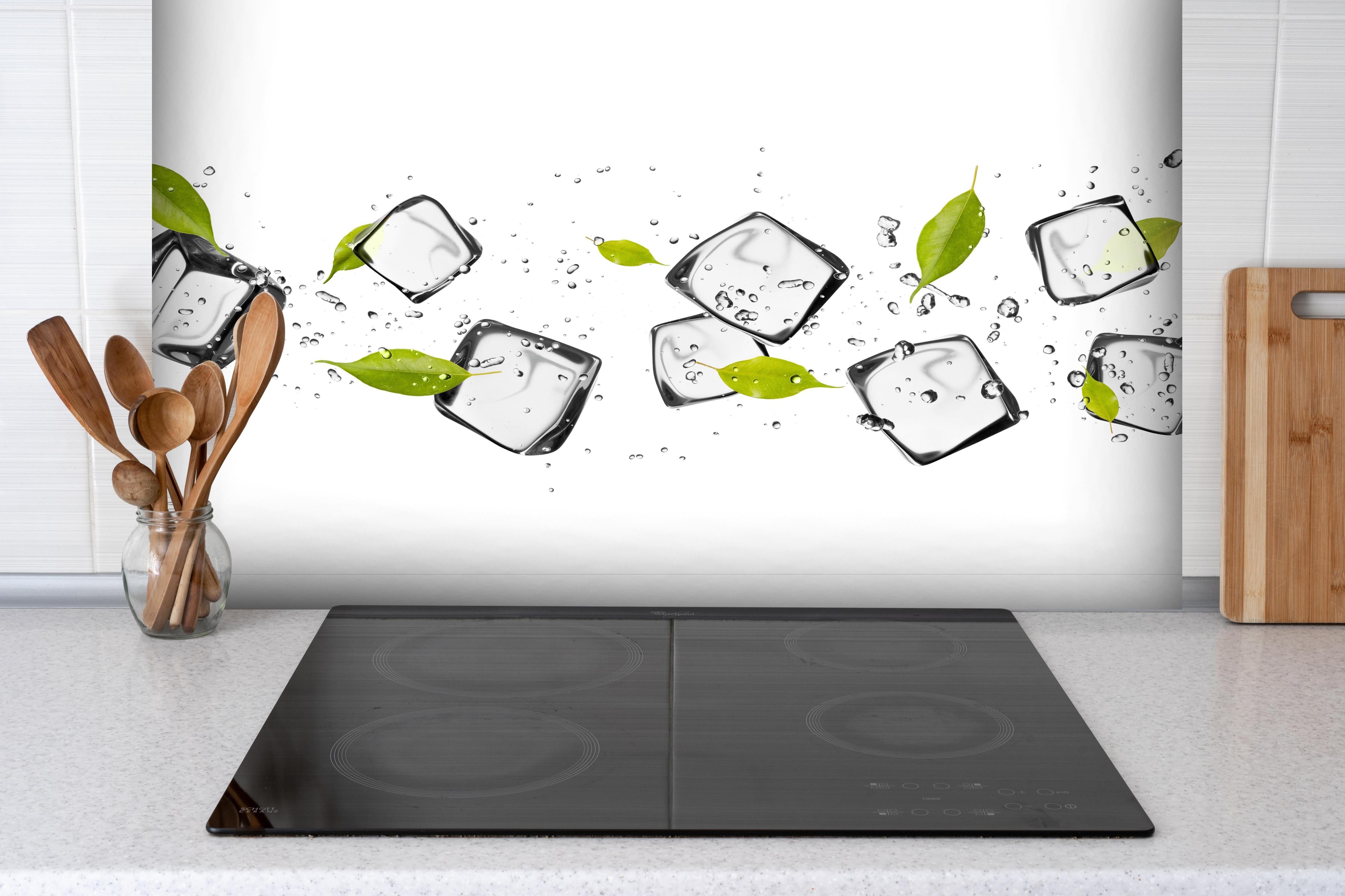 Spritzschutz - Eiswürfel mit Blättern hinter einem Cerankochfeld zwischen Holz-Kochutensilien
