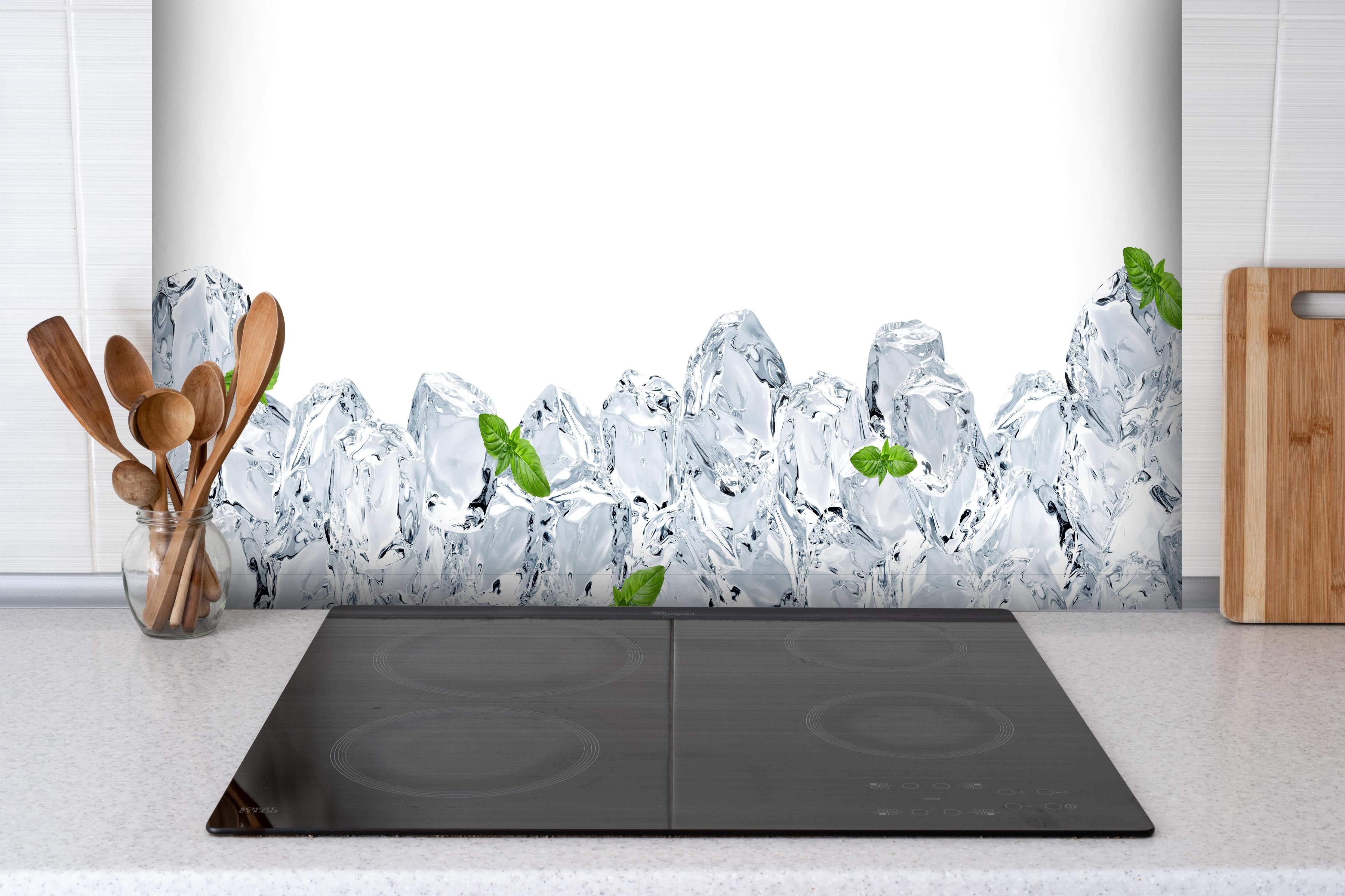 Spritzschutz - Eiswürfel mit einem hauch Minze hinter einem Cerankochfeld zwischen Holz-Kochutensilien
