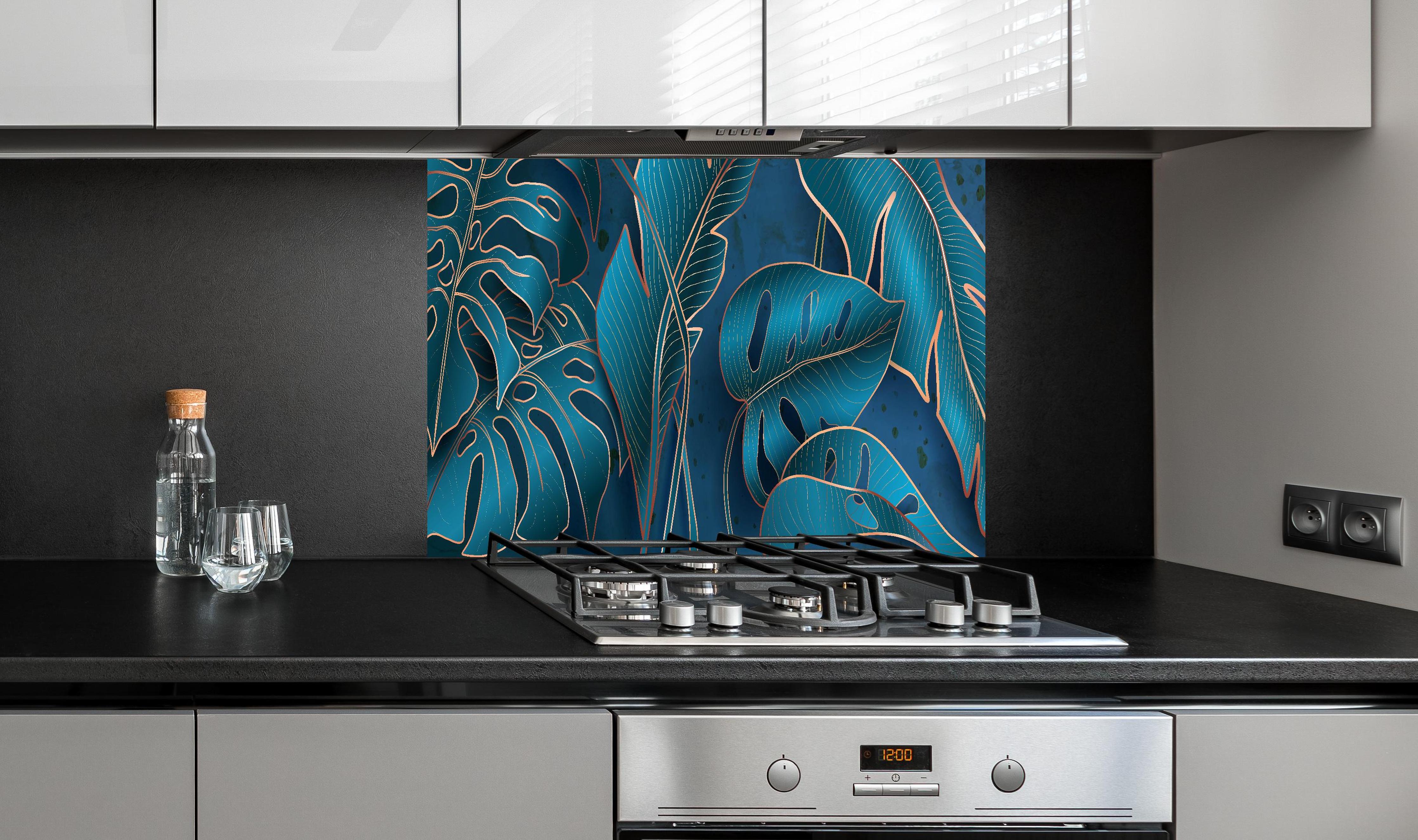 Spritzschutz - Elegante Blätter in Blau und Metallic-Tönen hinter einem Cerankochfeld zwischen Holz-Kochutensilien
