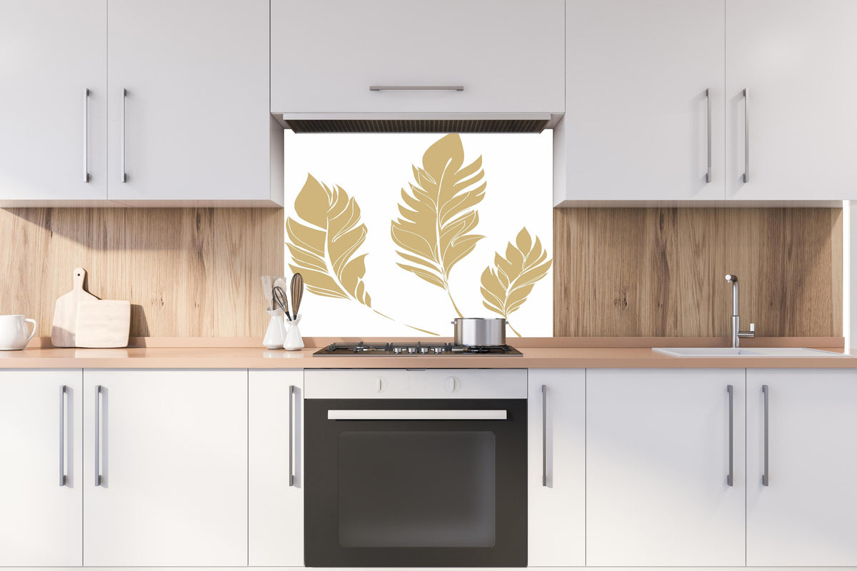 Spritzschutz - Elegante Goldfarbene Feder-Formen Set hinter einem Cerankochfeld zwischen Holz-Kochutensilien
