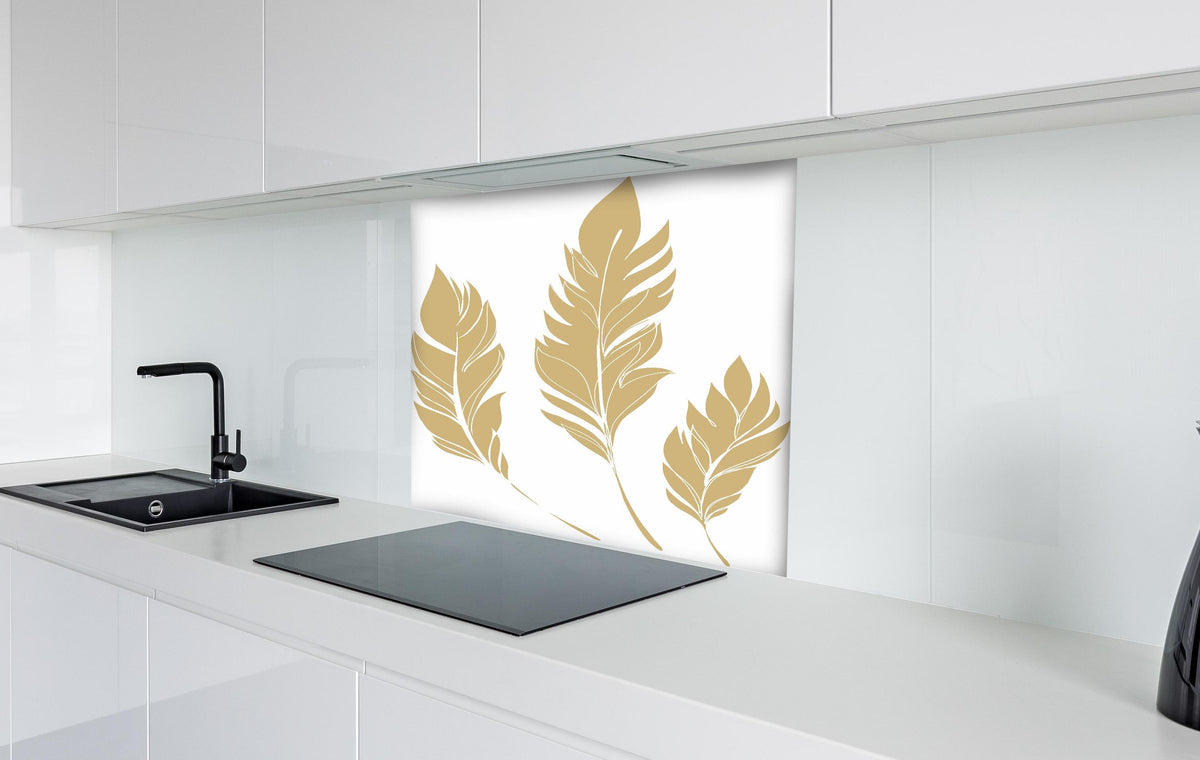 Spritzschutz - Elegante Goldfarbene Feder-Formen Set hinter einem Cerankochfeld zwischen Holz-Kochutensilien
