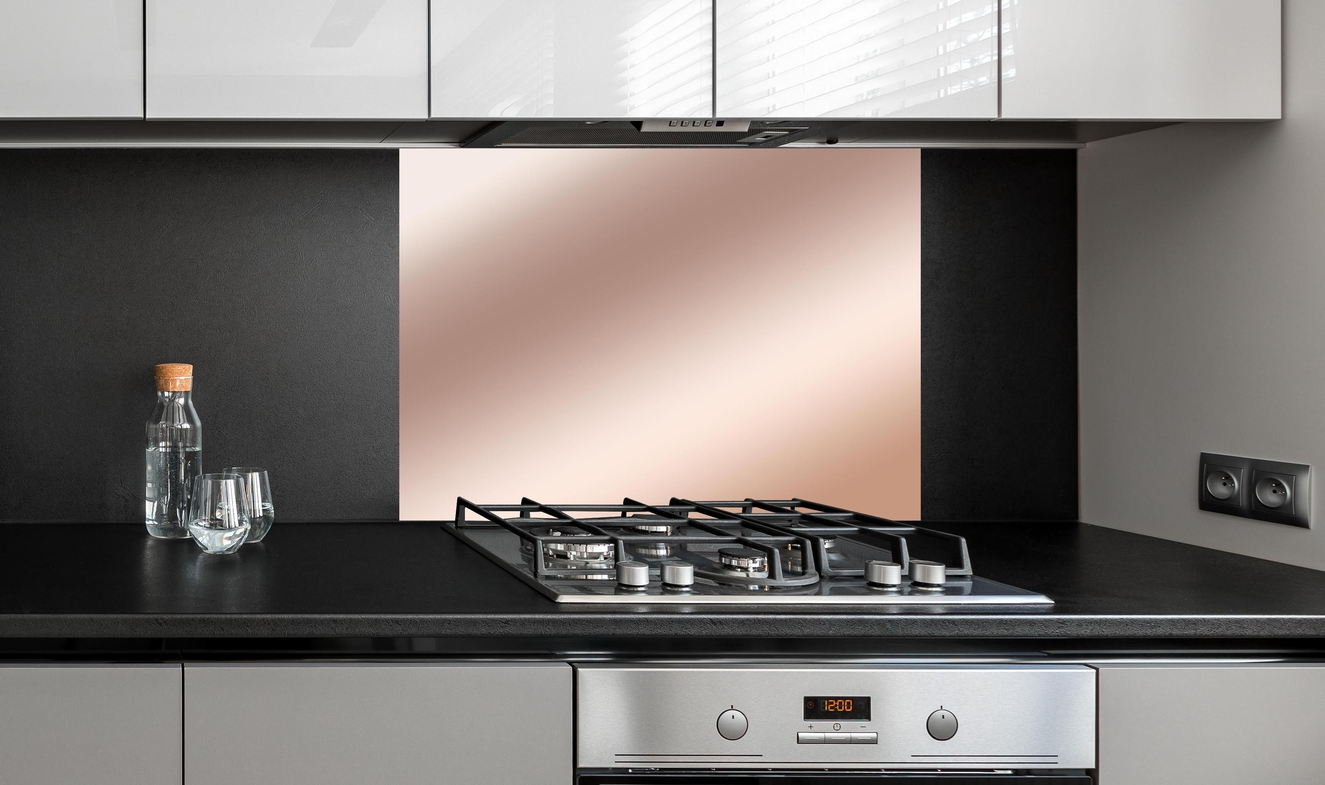 Spritzschutz - Elegante Metallic-Bronze Wand hinter einem Cerankochfeld zwischen Holz-Kochutensilien
