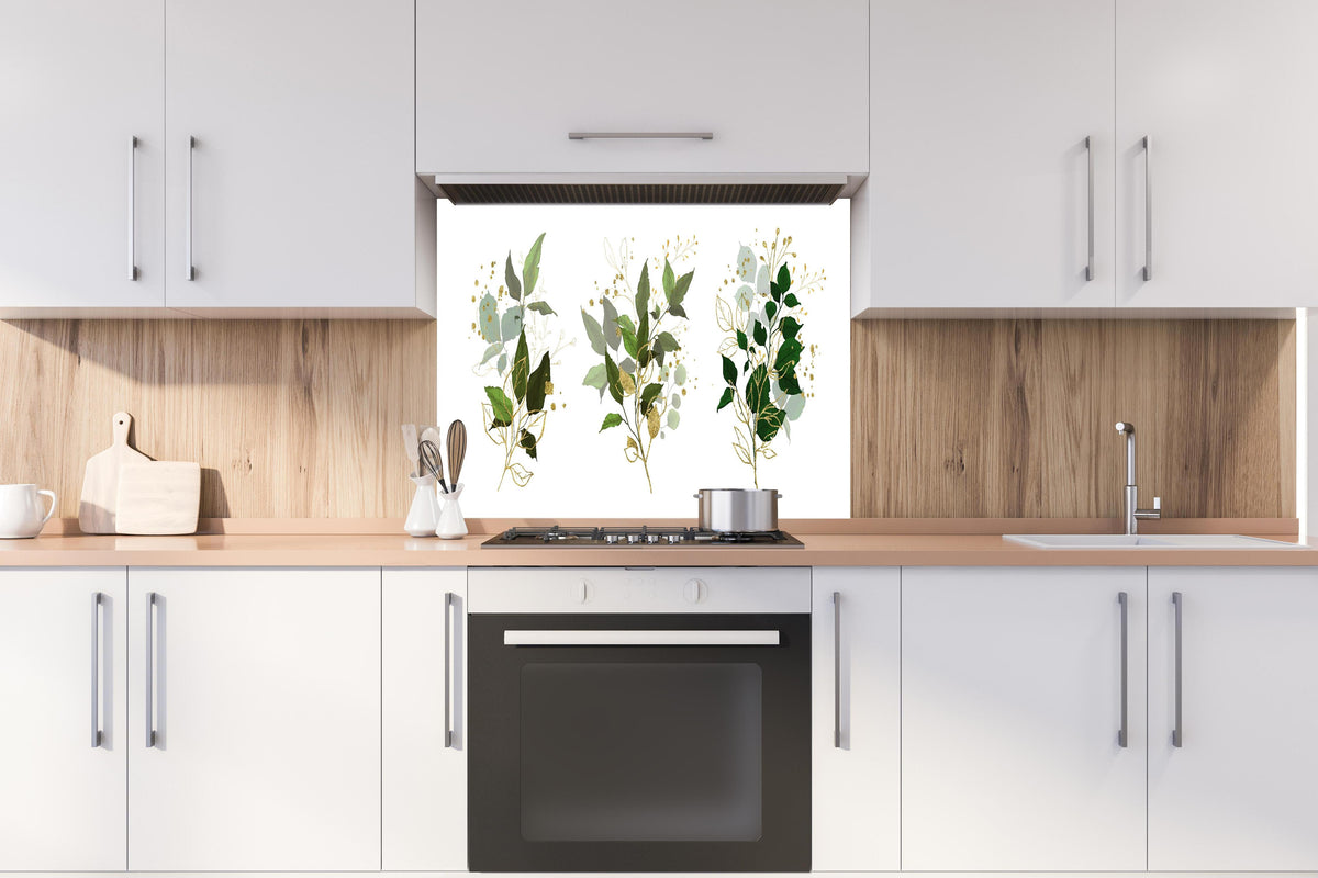 Spritzschutz - Elegante Pflanzenillustrationen in Goldtönen hinter einem Cerankochfeld zwischen Holz-Kochutensilien
