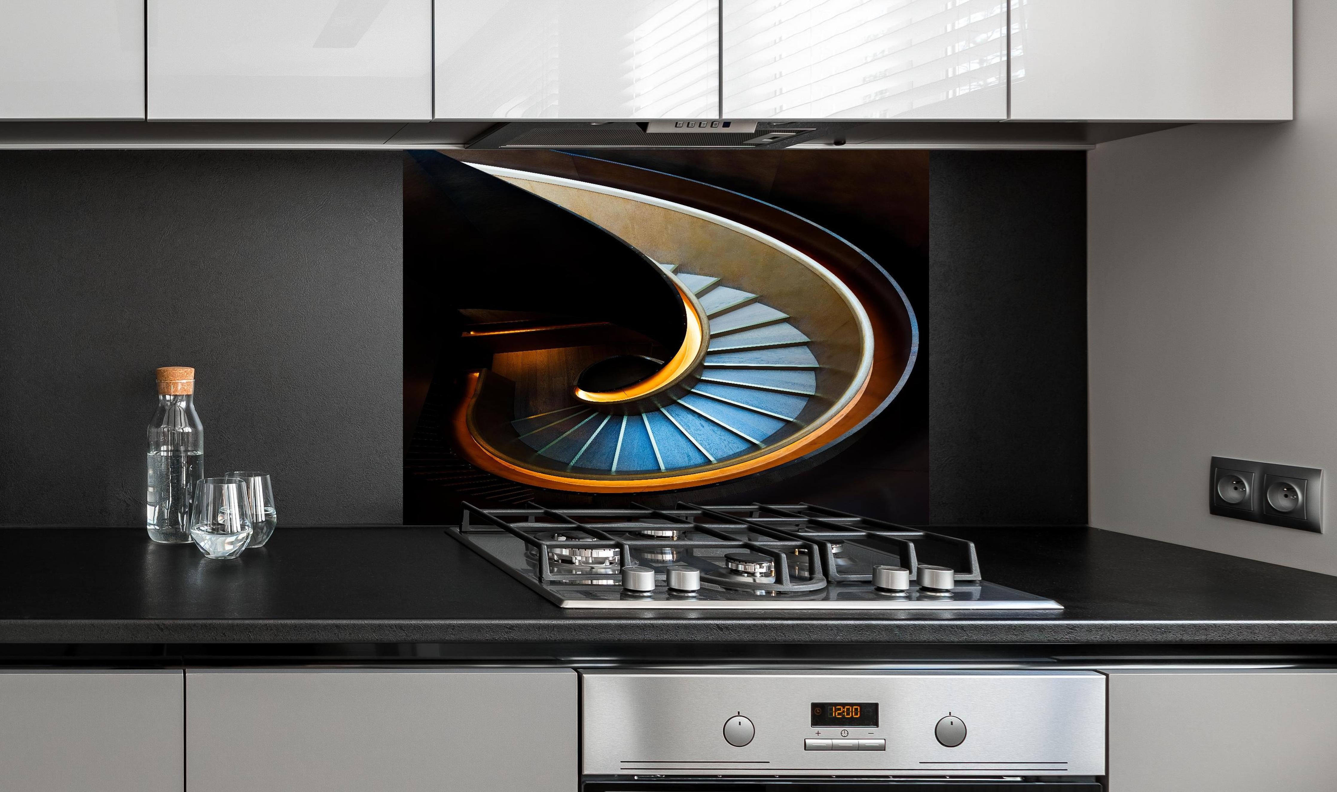 Spritzschutz - Elegante Spirale Treppenhaus Architektur hinter einem Cerankochfeld zwischen Holz-Kochutensilien
