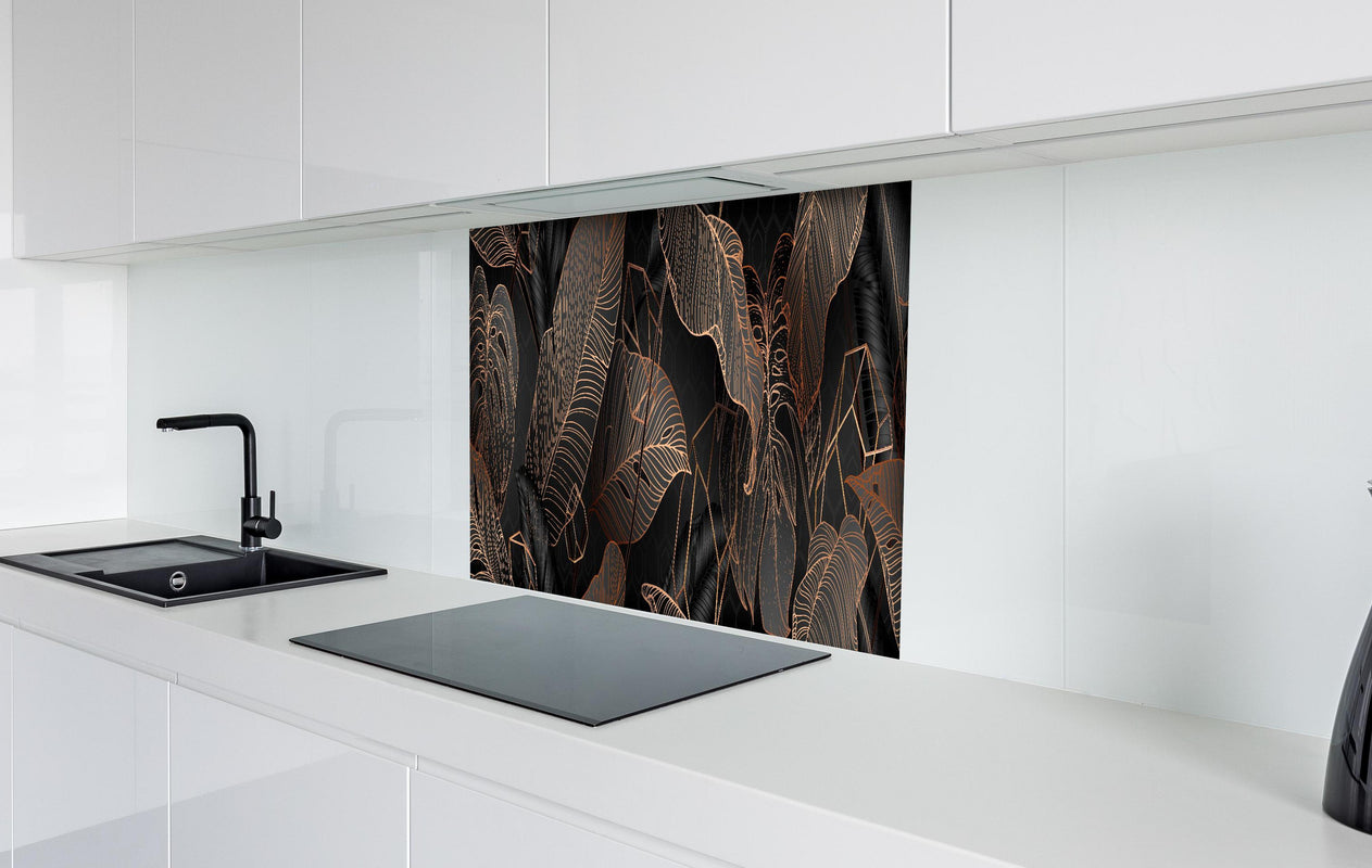 Spritzschutz - Elegante bronzene Blattlinien auf Schwarz hinter einem Cerankochfeld zwischen Holz-Kochutensilien
