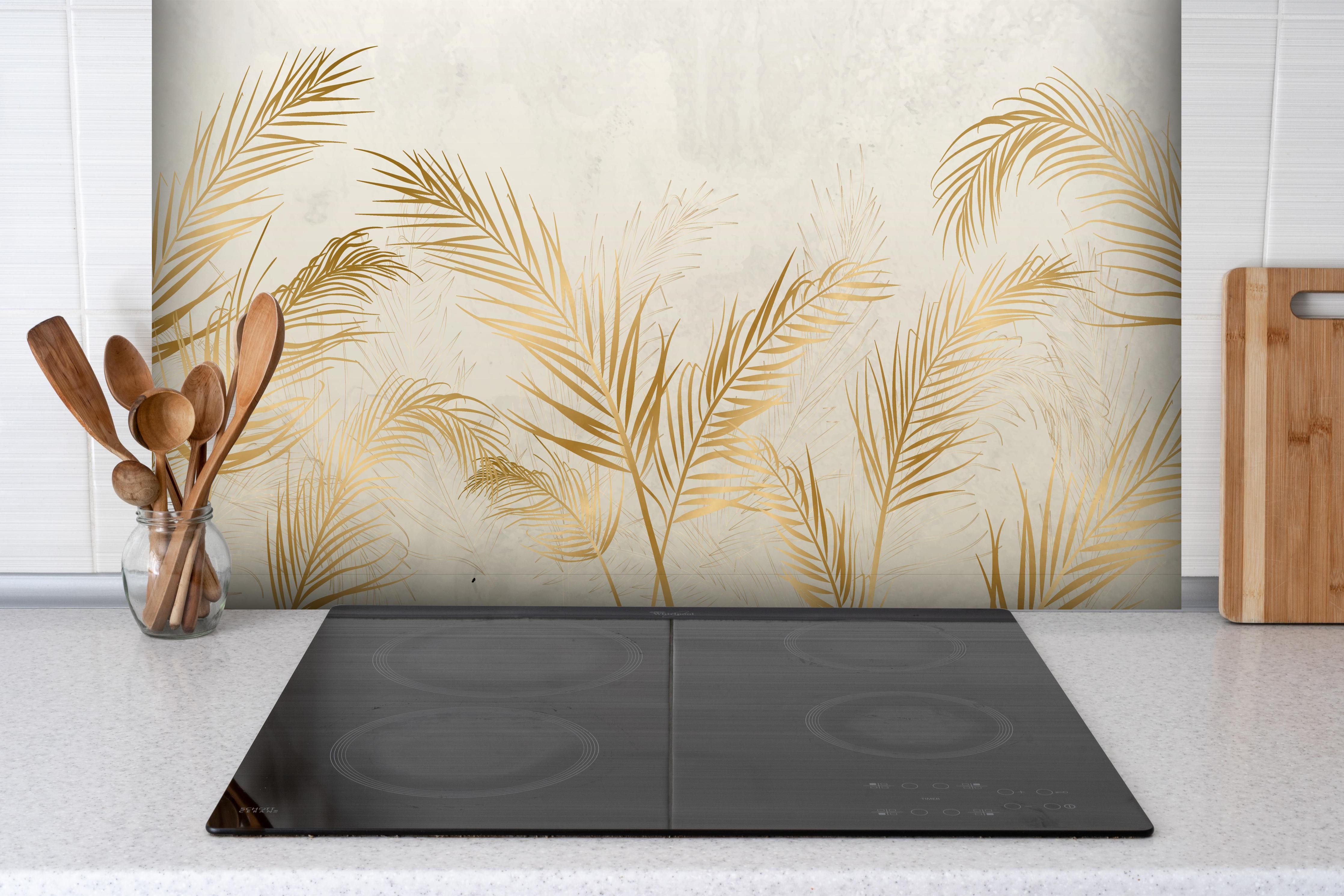 Spritzschutz - Elegante goldene Palmwedel auf hellem Grund hinter einem Cerankochfeld zwischen Holz-Kochutensilien
