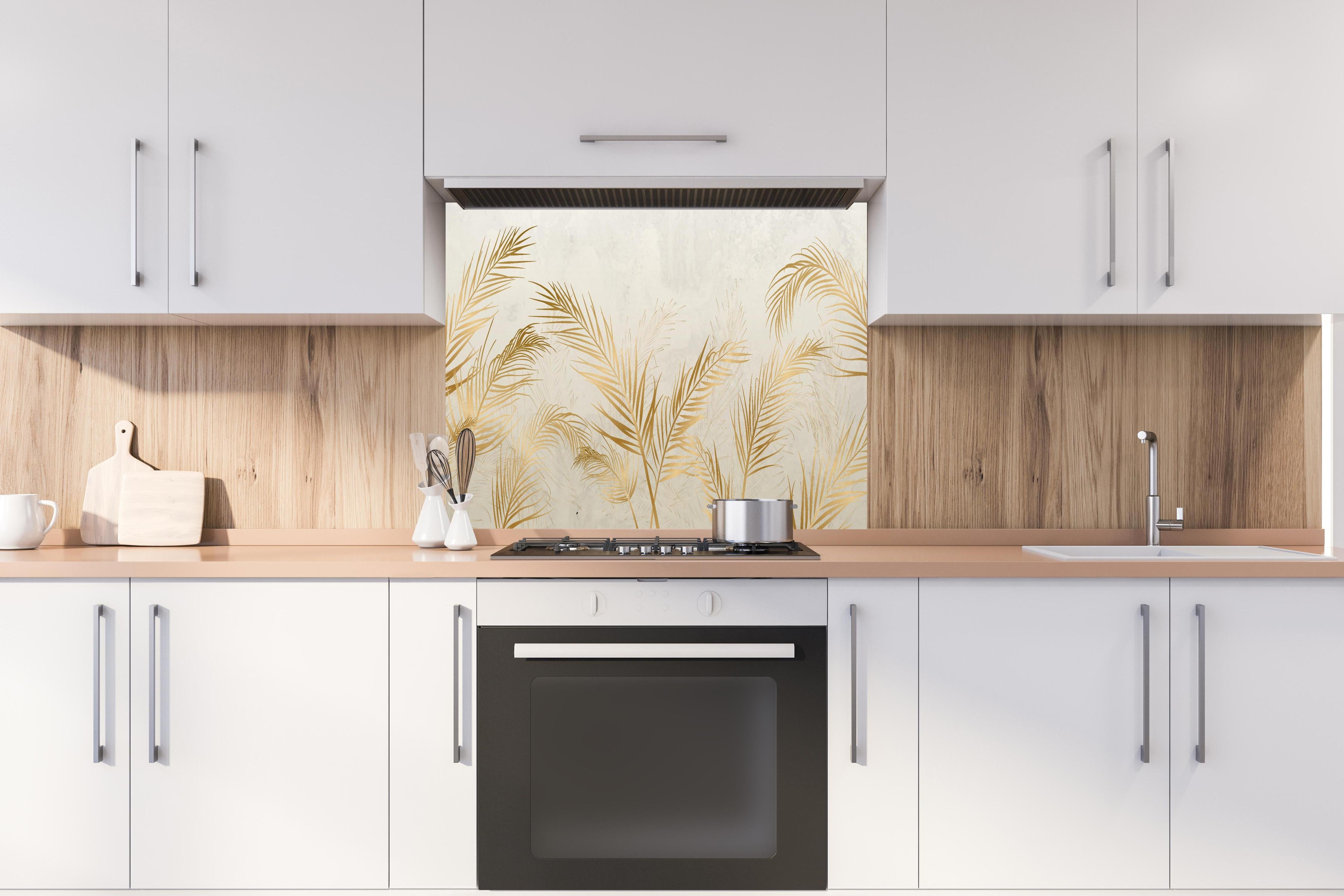 Spritzschutz - Elegante goldene Palmwedel auf hellem Grund hinter einem Cerankochfeld zwischen Holz-Kochutensilien
