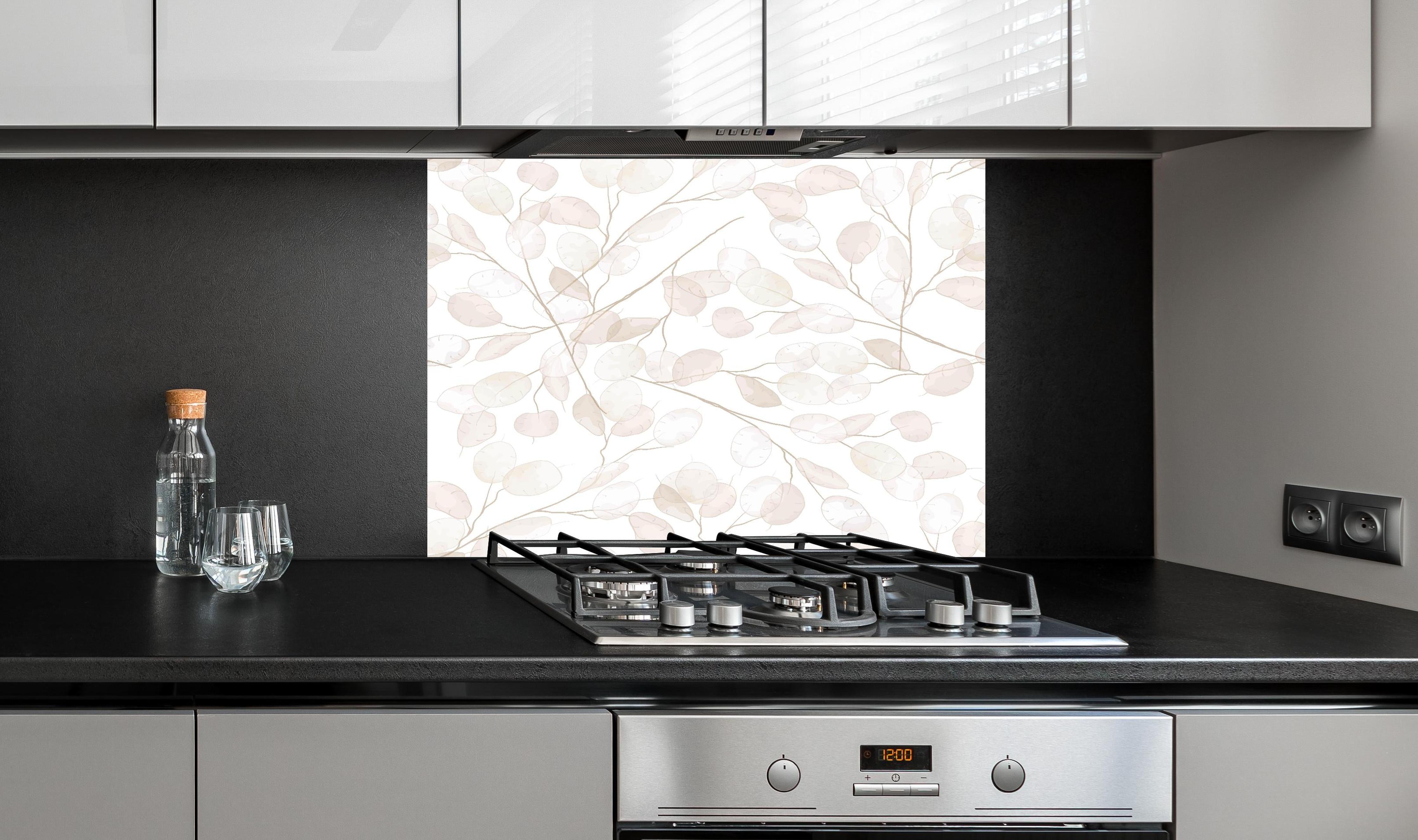 Spritzschutz - Elegante weiße Blätter mit Grauakzenten hinter einem Cerankochfeld zwischen Holz-Kochutensilien
