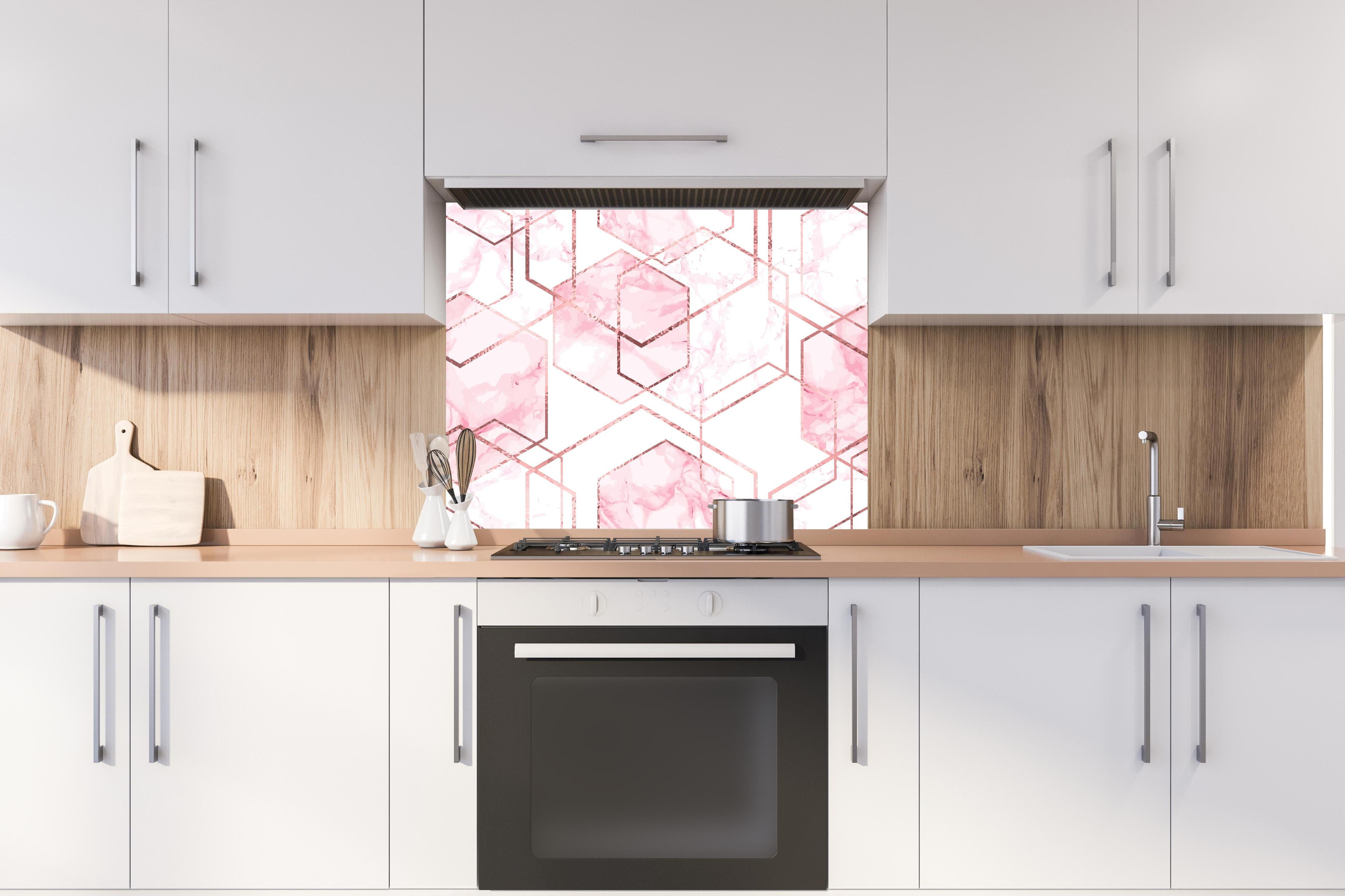 Spritzschutz - Eleganter rosa Marmor mit goldenen Linien hinter einem Cerankochfeld zwischen Holz-Kochutensilien
