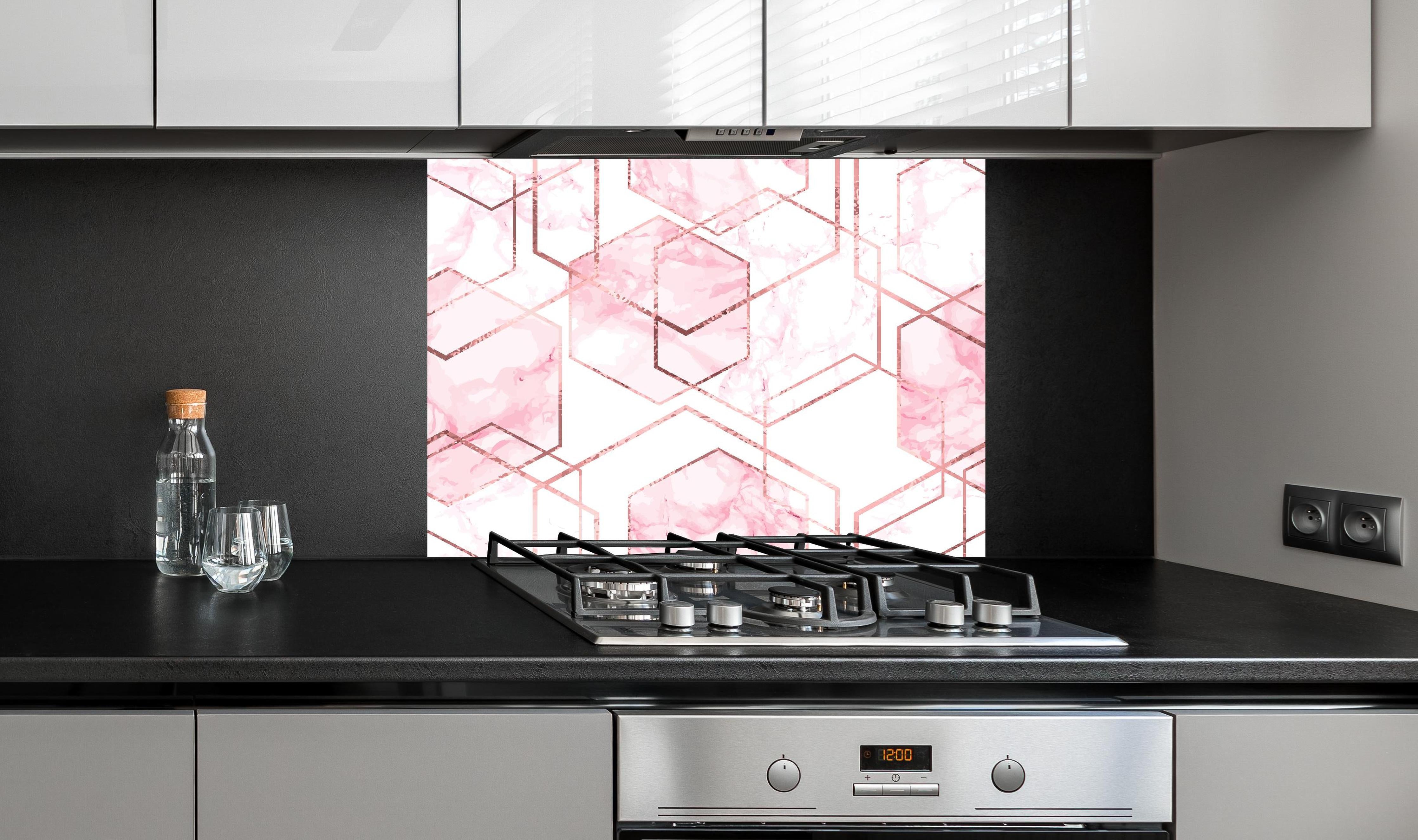 Spritzschutz - Eleganter rosa Marmor mit goldenen Linien hinter einem Cerankochfeld zwischen Holz-Kochutensilien
