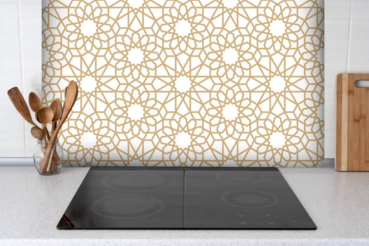 Spritzschutz - Elegantes Arabesken Design in Gold und Weiß hinter einem Cerankochfeld zwischen Holz-Kochutensilien
