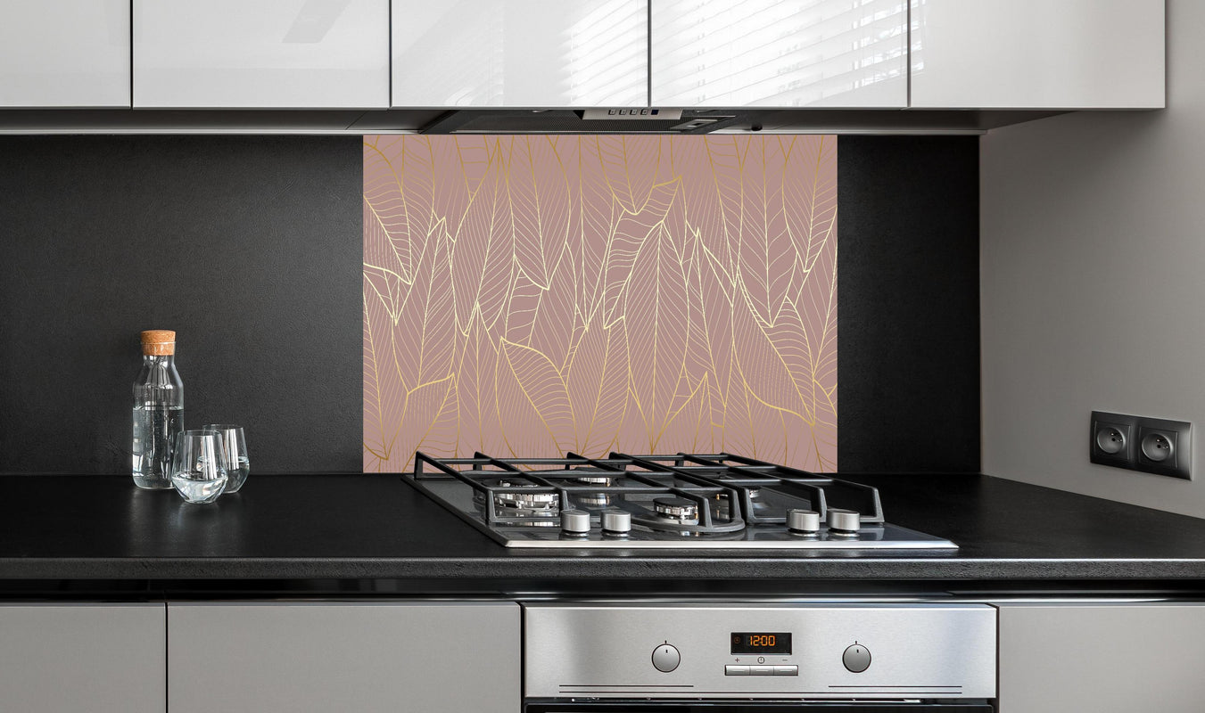 Spritzschutz - Elegantes Blattgold-Muster auf Taupe-Hintergrund hinter einem Cerankochfeld zwischen Holz-Kochutensilien
