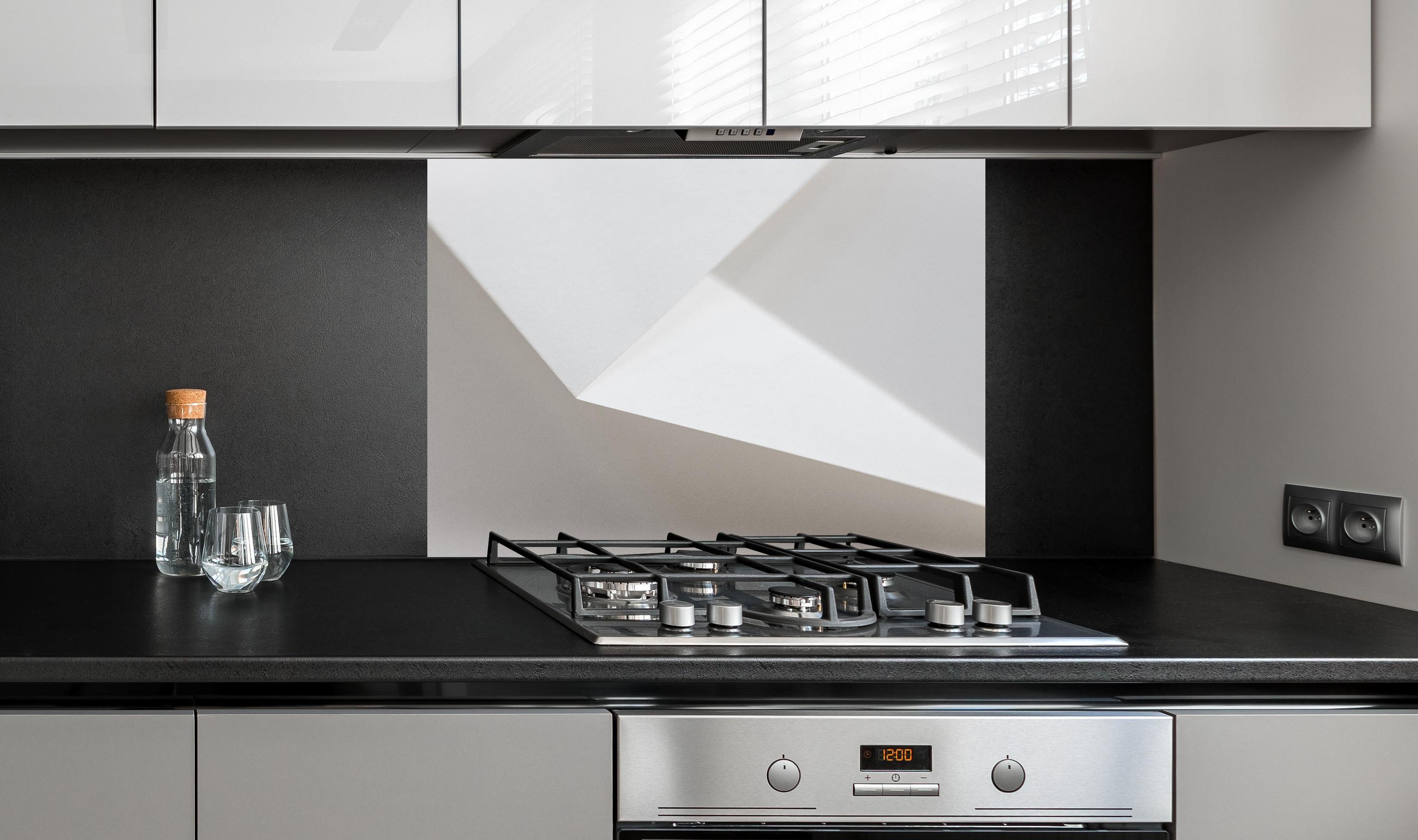 Spritzschutz - Elegantes Design Weiß und Schatten-Textur hinter einem Cerankochfeld zwischen Holz-Kochutensilien
