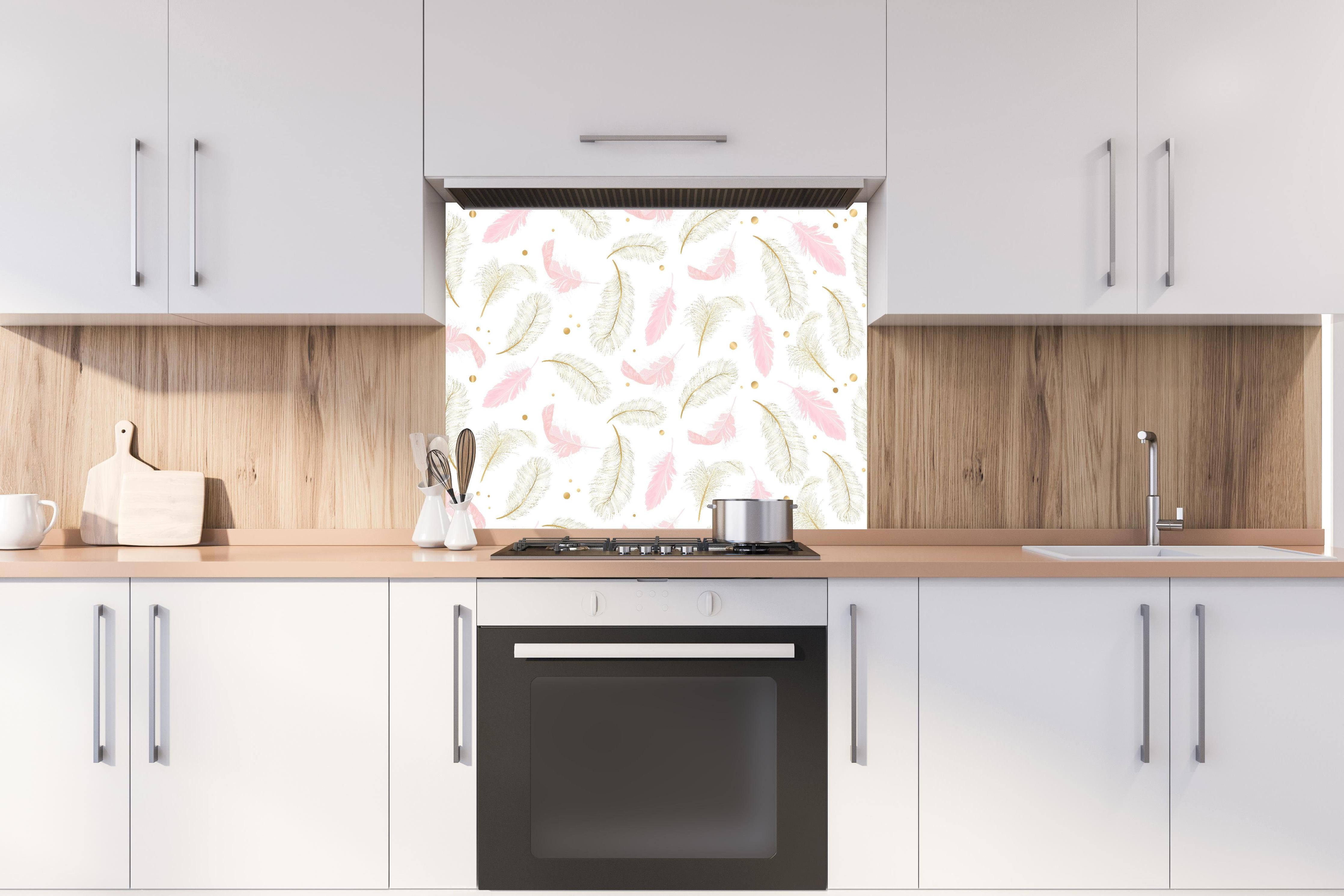 Spritzschutz - Elegantes Feder-Muster in Rosa und Goldtönen hinter einem Cerankochfeld zwischen Holz-Kochutensilien
