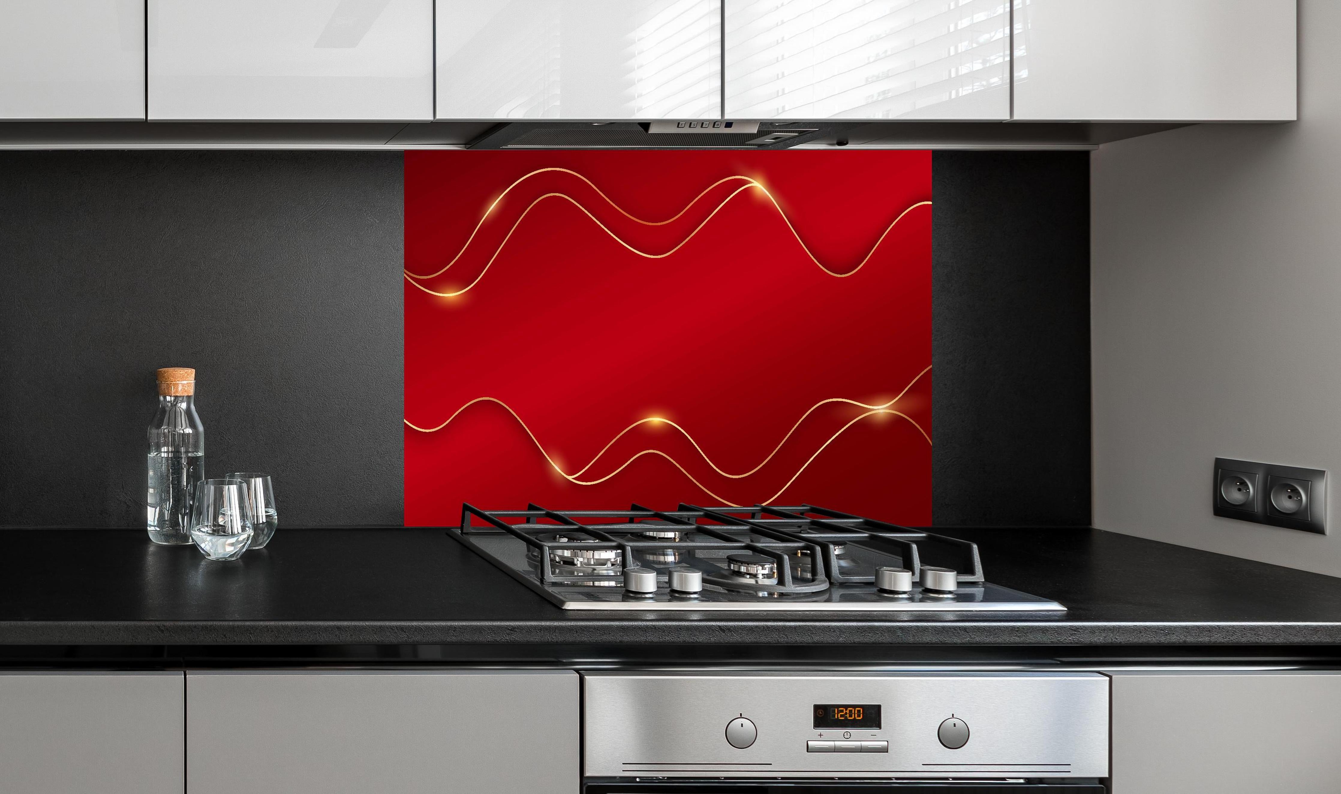 Spritzschutz - Elegantes Rot mit luxuriösen Goldlinien hinter einem Cerankochfeld zwischen Holz-Kochutensilien
