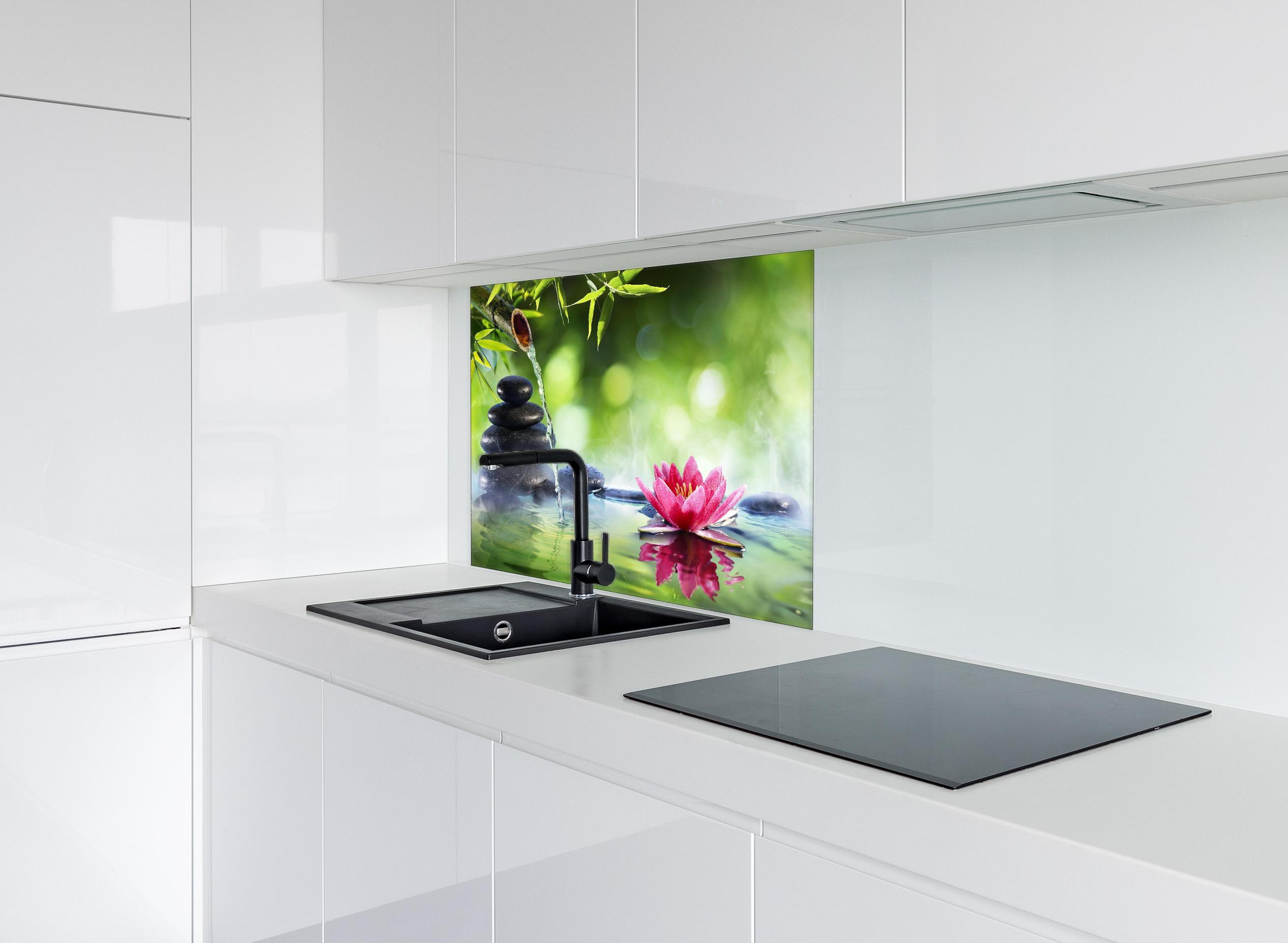 Spritzschutz - Entspannende Zen-Steine und pinkfarbene Lotusblüte hinter einem Cerankochfeld zwischen Holz-Kochutensilien
