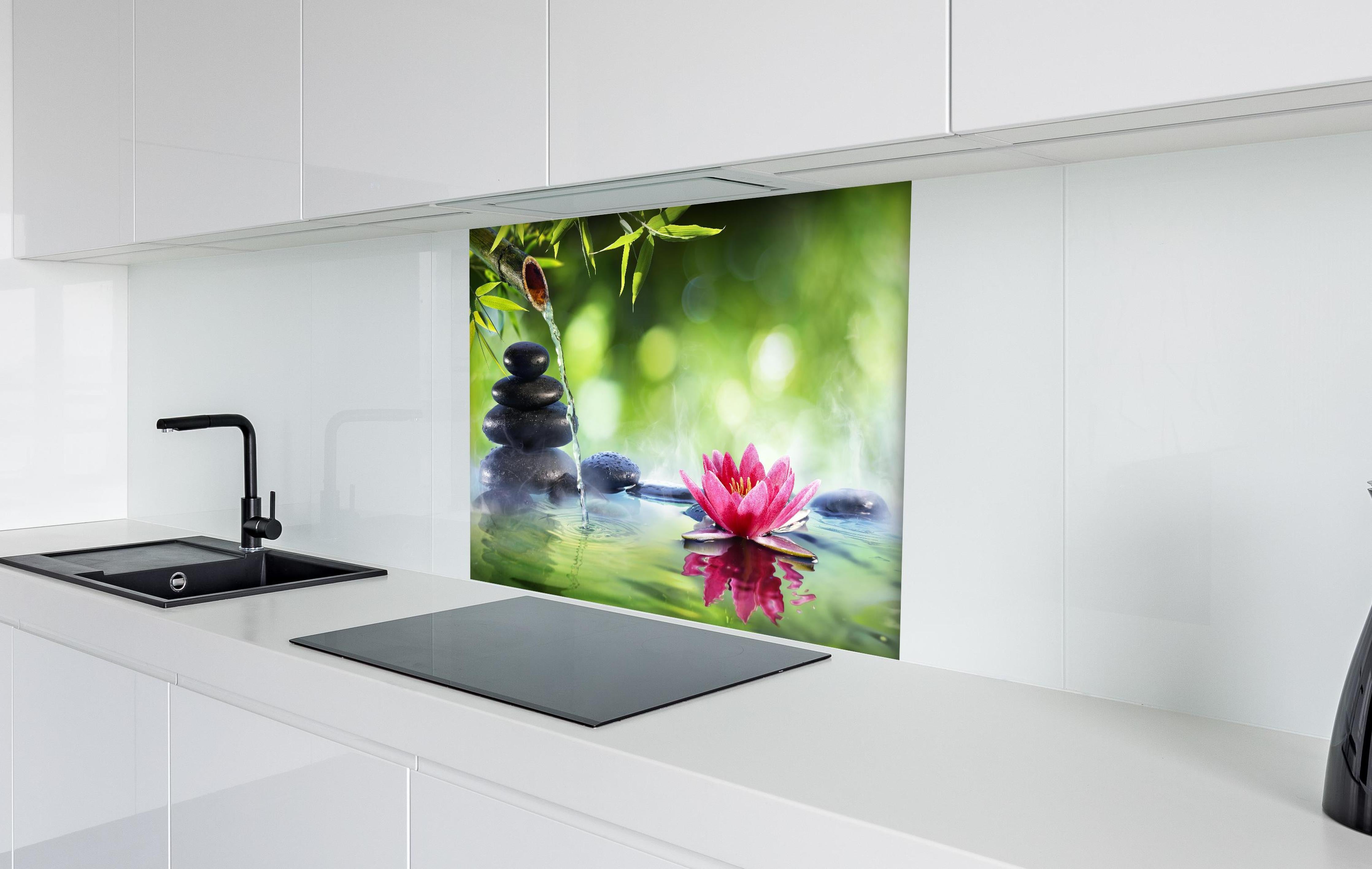 Spritzschutz - Entspannende Zen-Steine und pinkfarbene Lotusblüte hinter einem Cerankochfeld zwischen Holz-Kochutensilien
