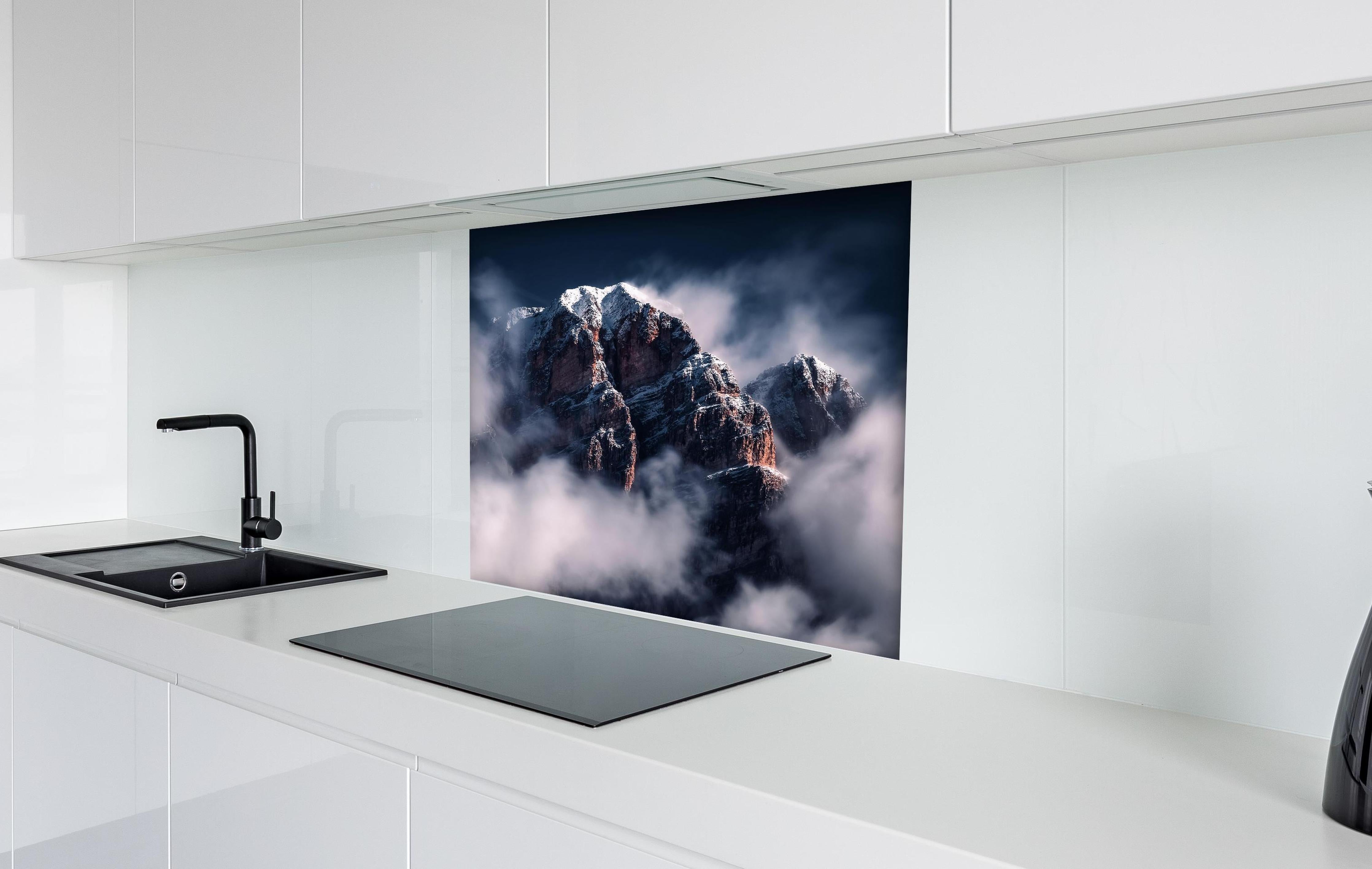 Spritzschutz - Erhabene Winterberge in Nebel und Schnee hinter einem Cerankochfeld zwischen Holz-Kochutensilien
