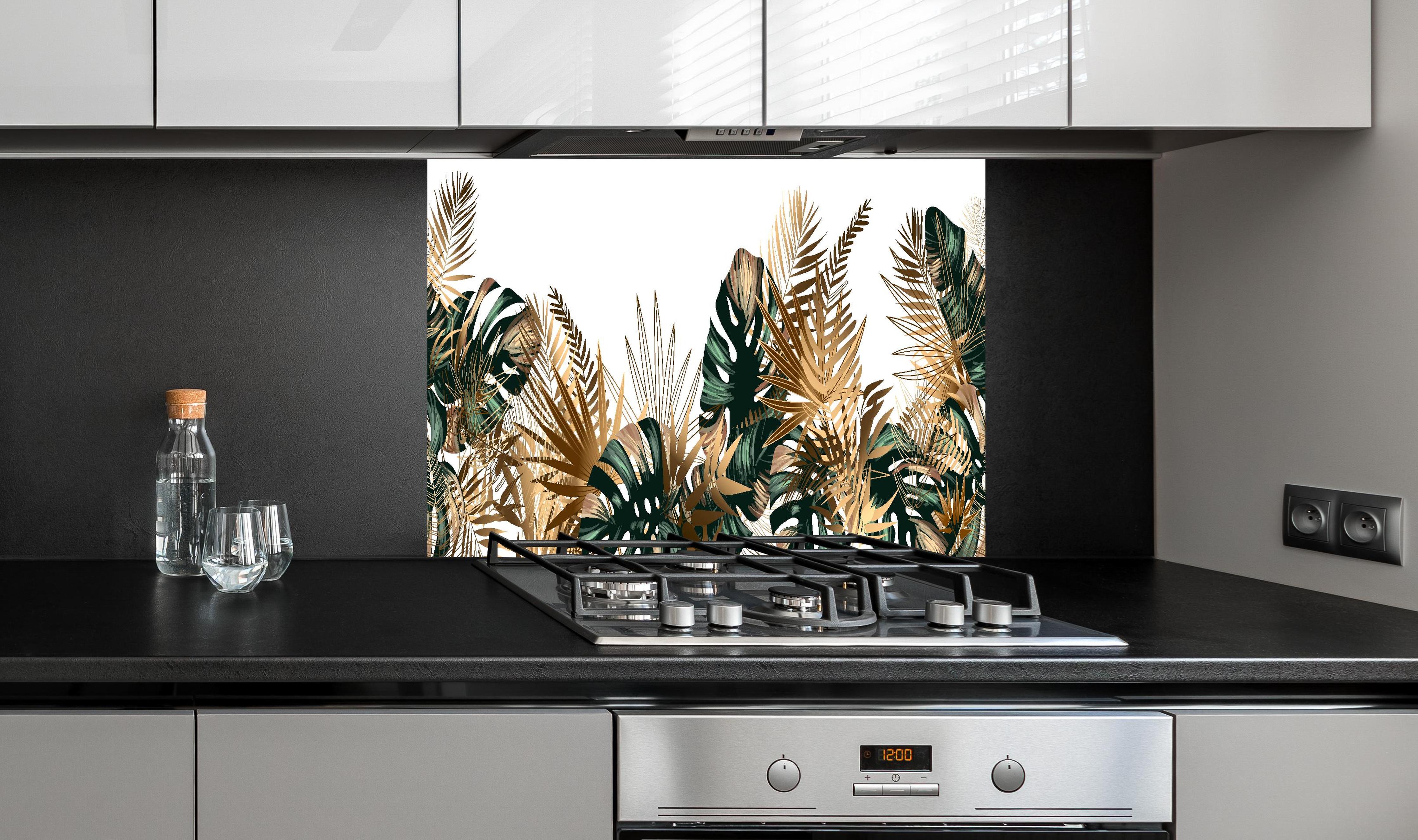 Spritzschutz - Exotisches Gold-Grün Palmenblatt Muster hinter einem Cerankochfeld zwischen Holz-Kochutensilien
