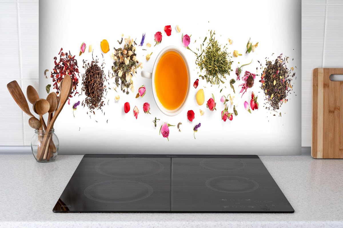 Spritzschutz - Exquisite Teesorten umgeben von Blumen hinter einem Cerankochfeld zwischen Holz-Kochutensilien
