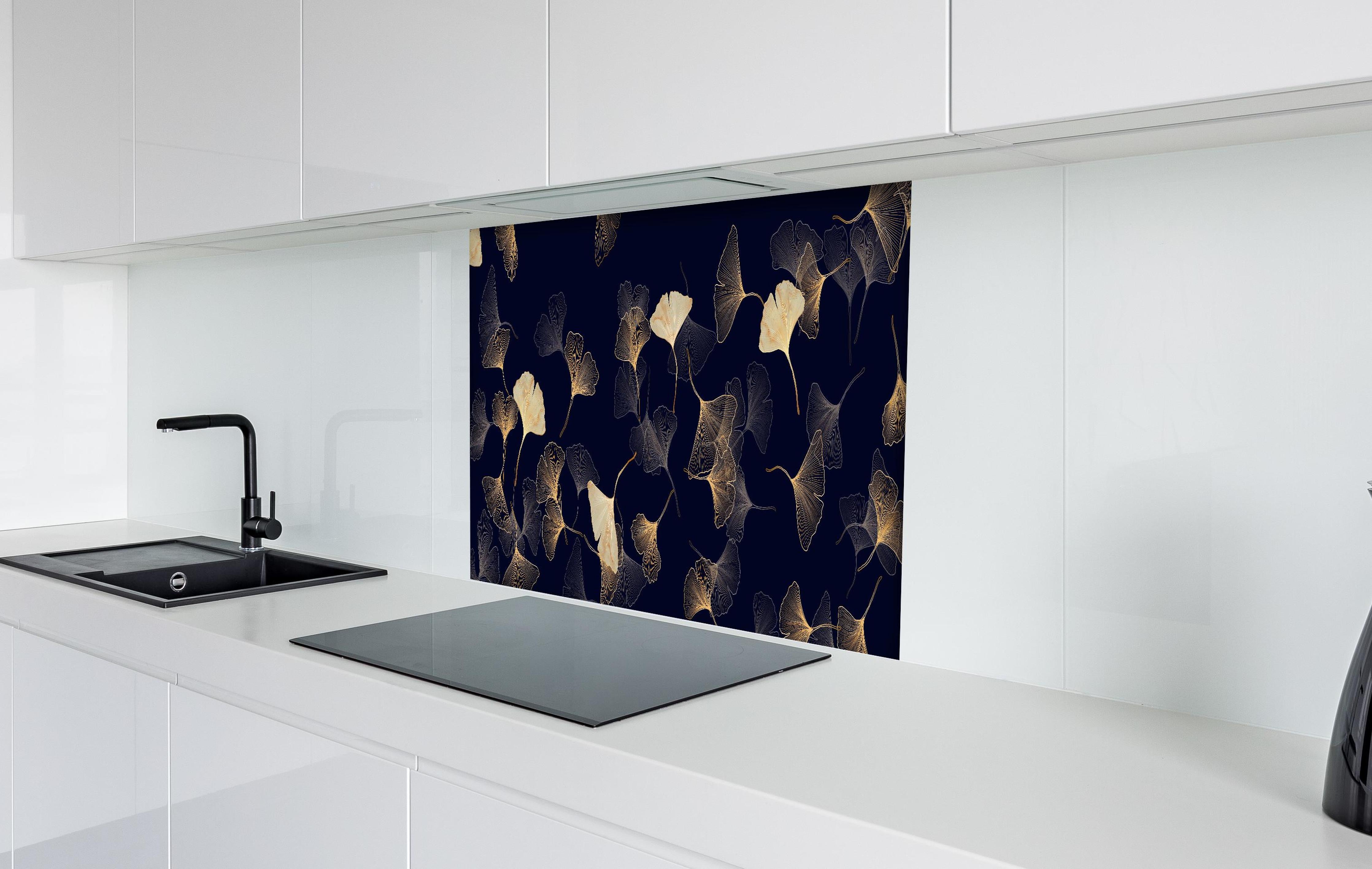 Spritzschutz - Exquisite goldene Ginkgo Blätter auf dunklem Hintergrund hinter einem Cerankochfeld zwischen Holz-Kochutensilien
