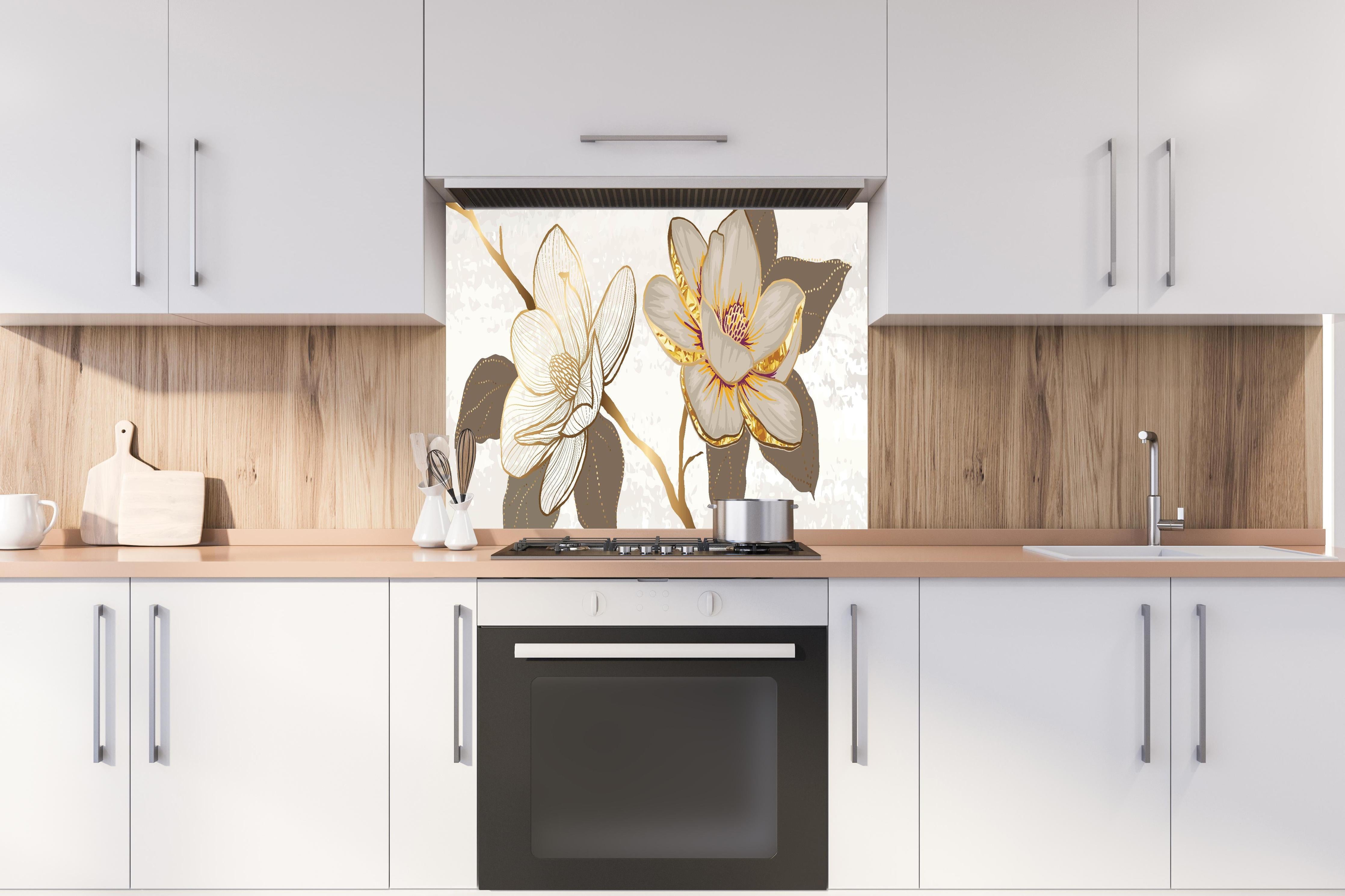 Spritzschutz - Exquisites Magnolienmuster in Gold und Beige hinter einem Cerankochfeld zwischen Holz-Kochutensilien
