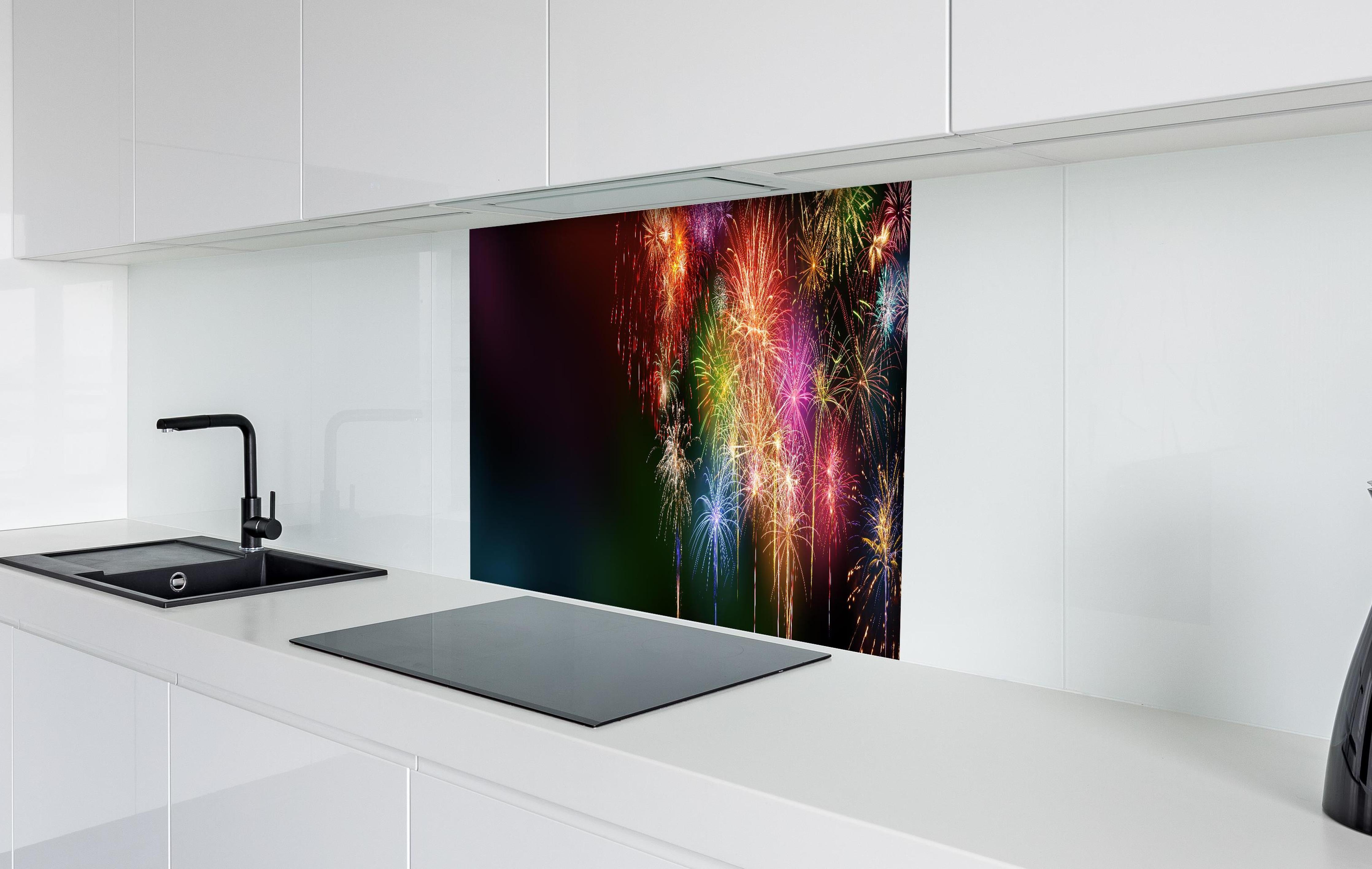 Spritzschutz - Farbenfrohe Feuerwerk-Show am Nachthimmel hinter einem Cerankochfeld zwischen Holz-Kochutensilien
