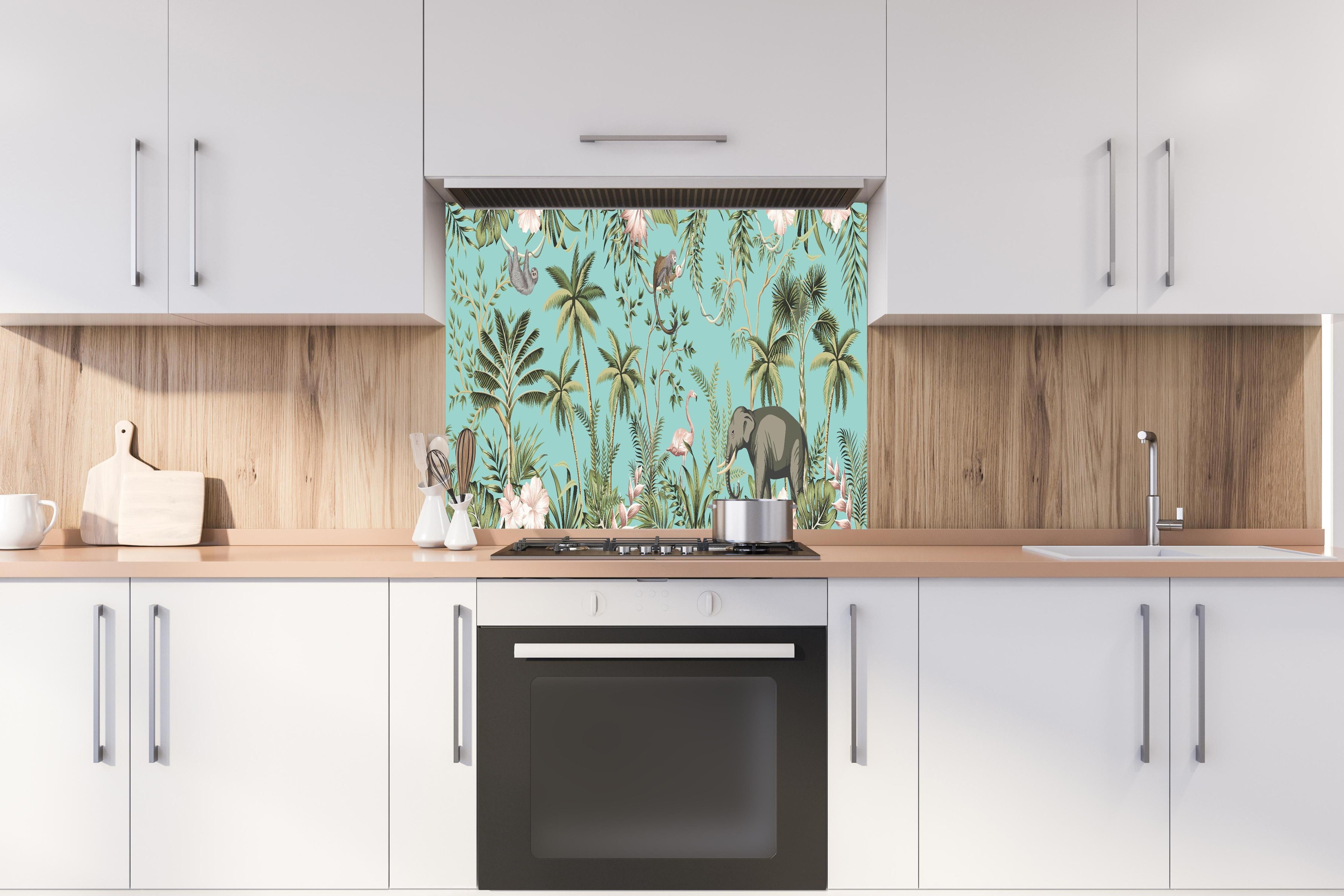 Spritzschutz - Farbenfrohes Dschungel-Muster auf Textil hinter einem Cerankochfeld zwischen Holz-Kochutensilien
