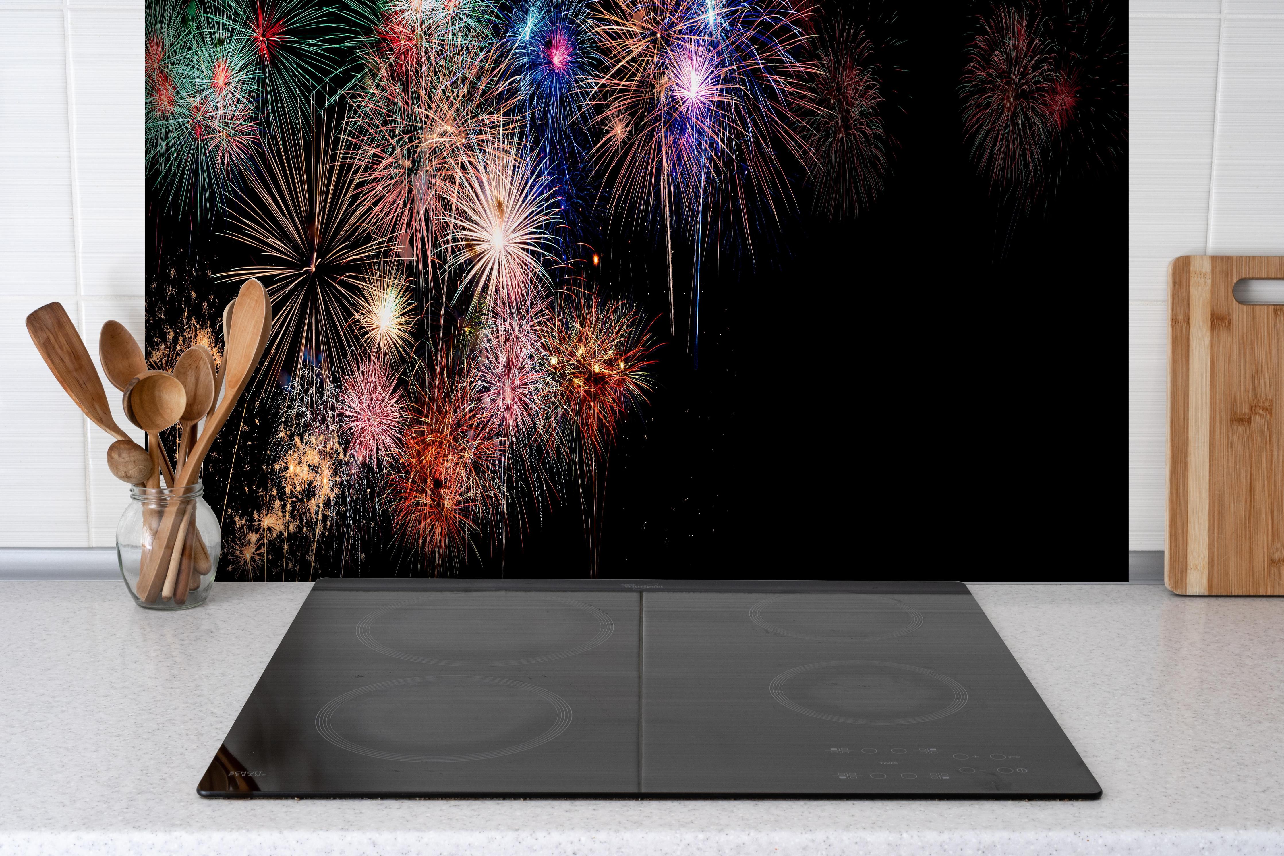 Spritzschutz - Farbenpracht Feuerwerk Happy New Year 2023 hinter einem Cerankochfeld zwischen Holz-Kochutensilien
