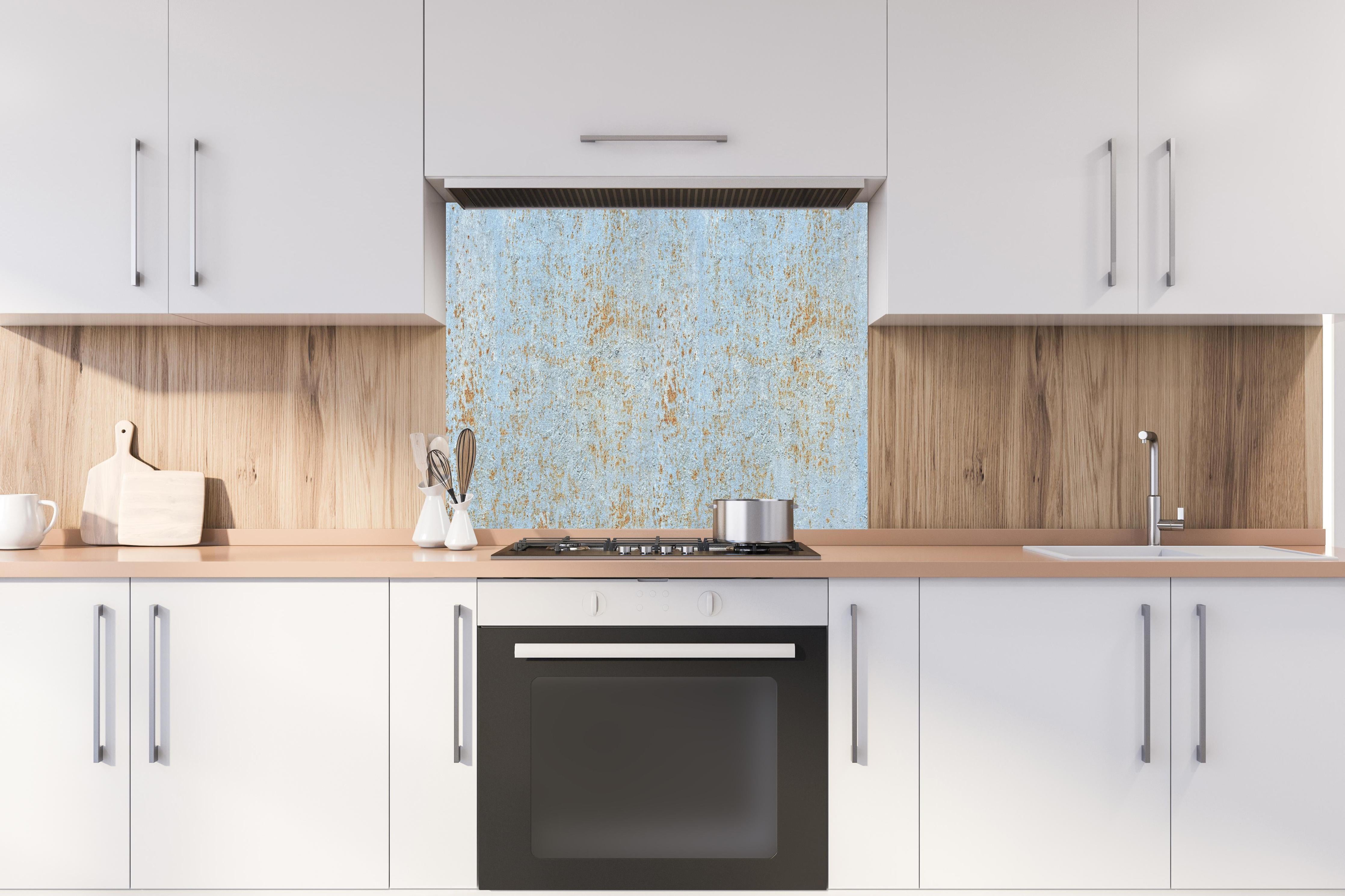 Spritzschutz - Farbflocken auf rostigem Metallblech hinter einem Cerankochfeld zwischen Holz-Kochutensilien
