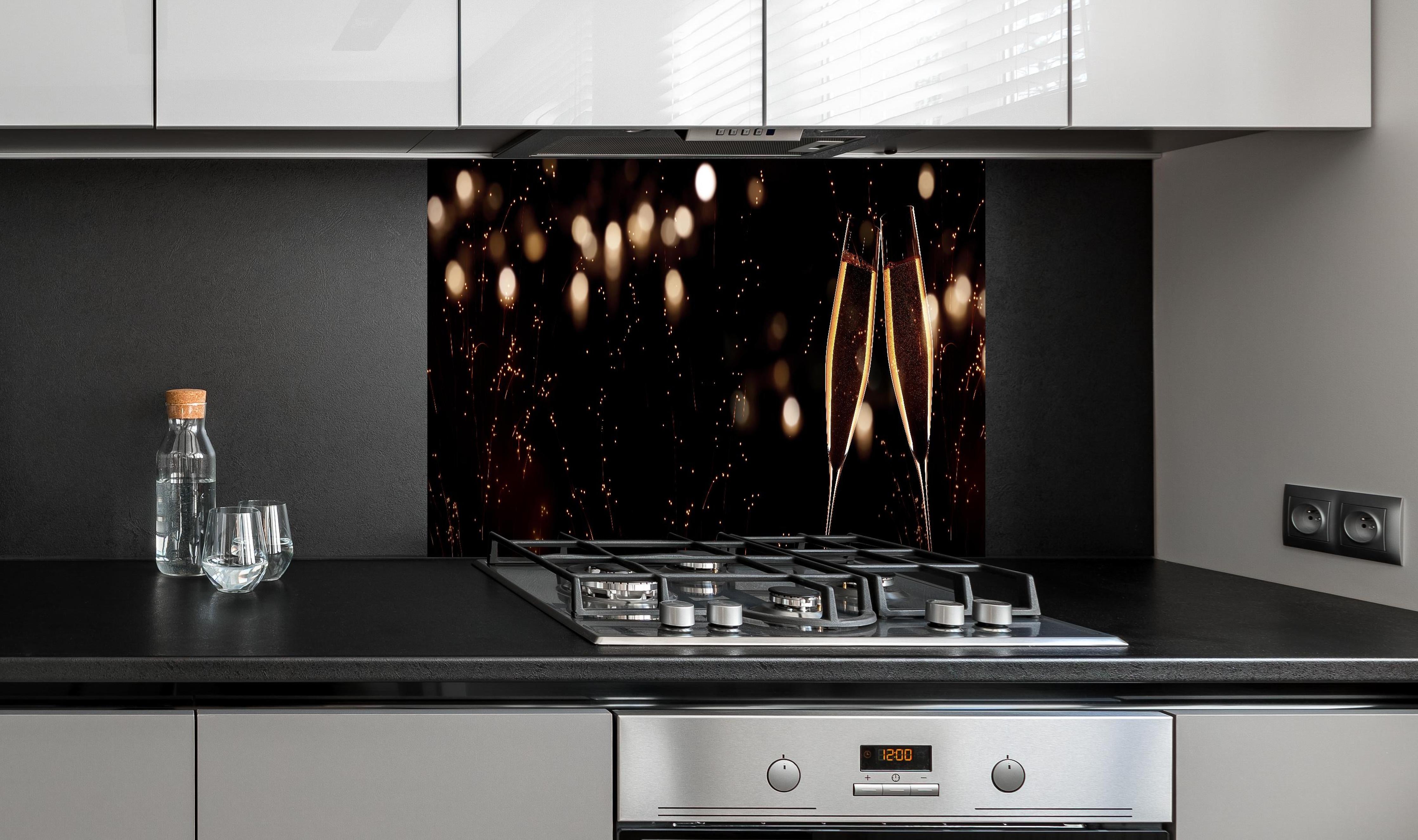 Spritzschutz - Feierlicher Champagner-Clink bei Jahreswechsel hinter einem Cerankochfeld zwischen Holz-Kochutensilien
