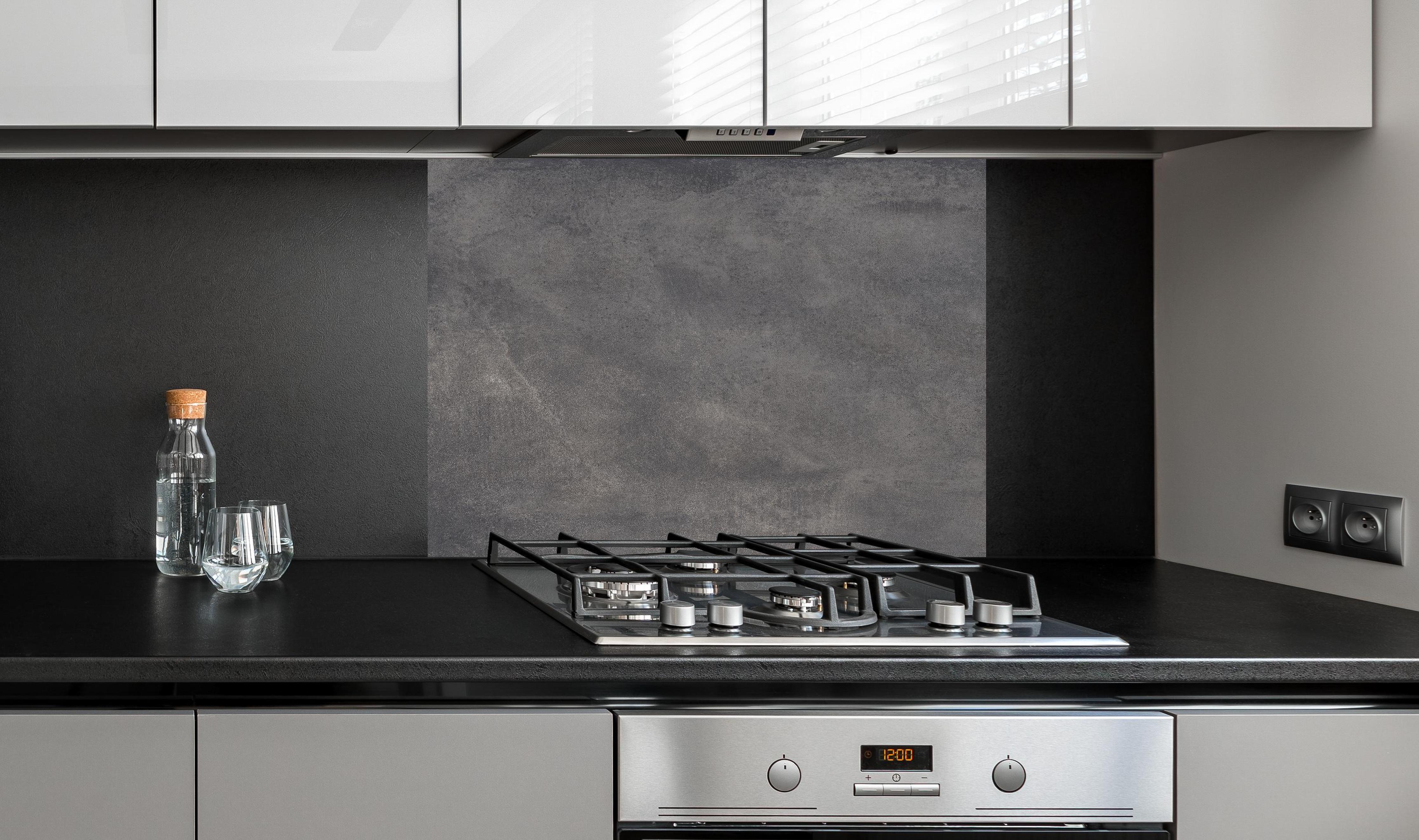 Spritzschutz - Feine dunkle Betonwand hinter einem Cerankochfeld zwischen Holz-Kochutensilien
