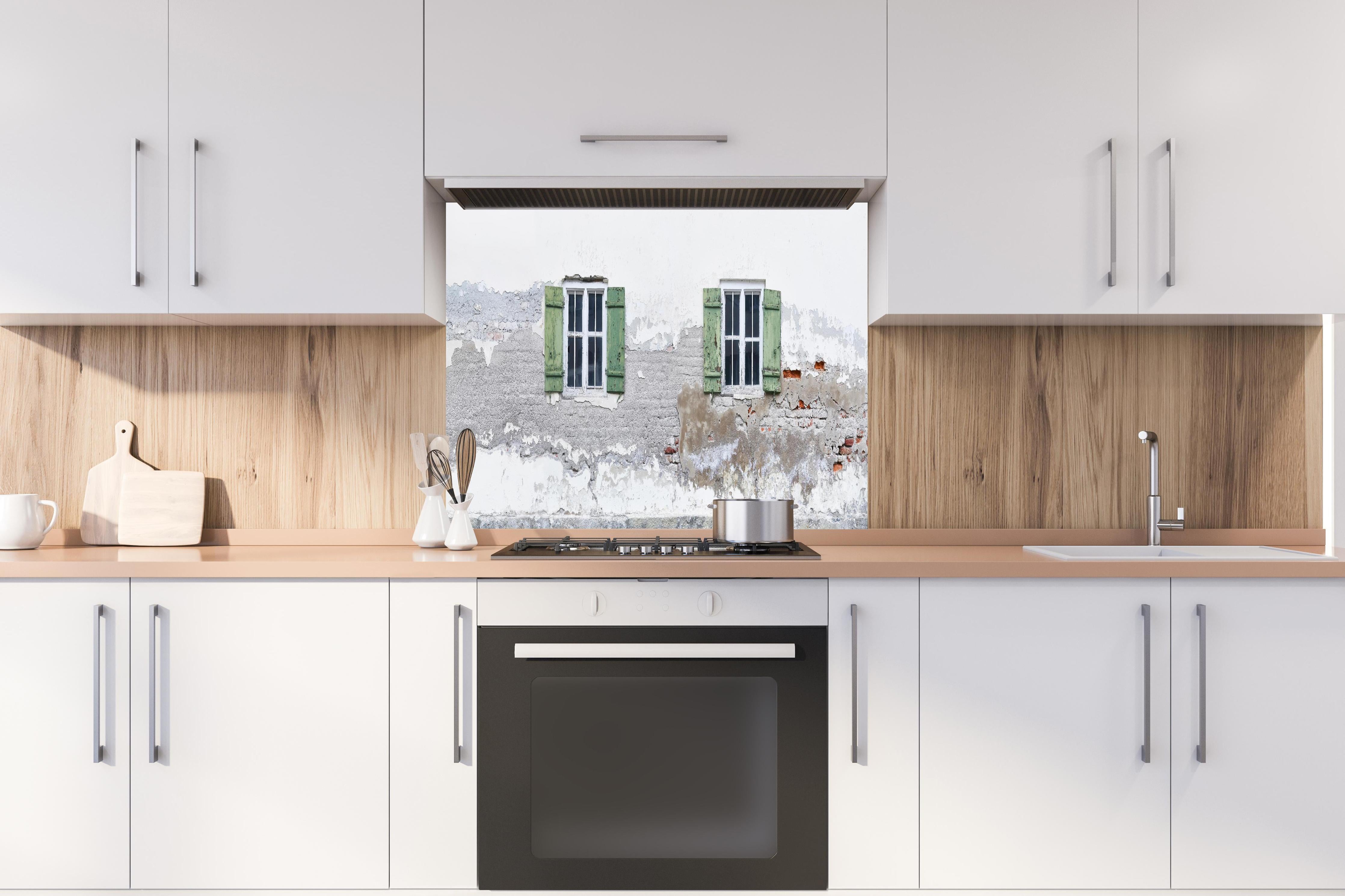 Spritzschutz - Fensterrahmen einer veralteten Hauswand hinter einem Cerankochfeld zwischen Holz-Kochutensilien
