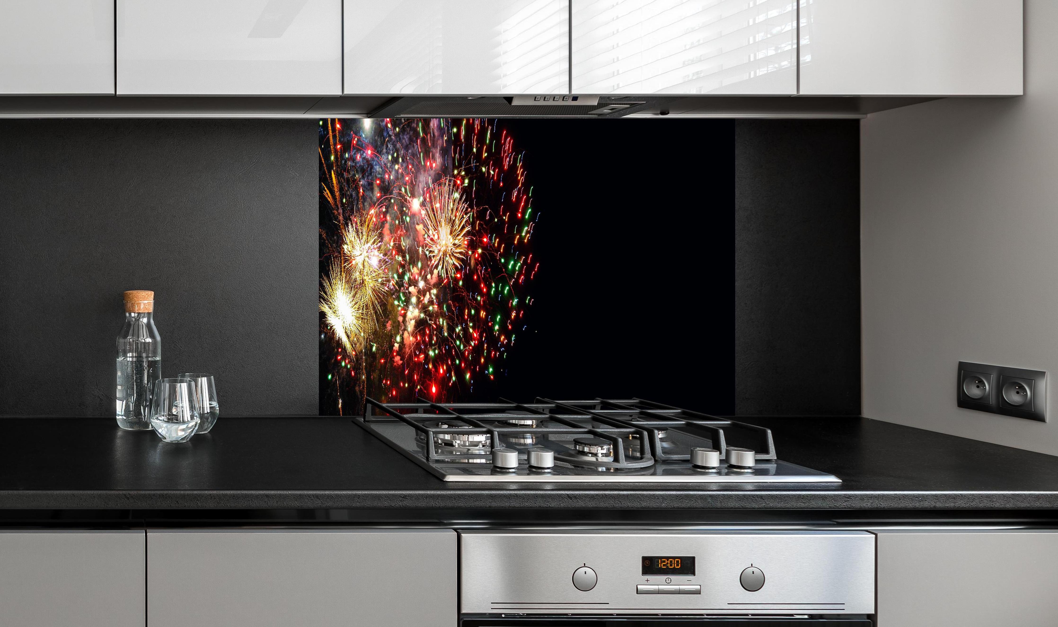 Spritzschutz - Feuerwerk Neujahr Bunt Nachthimmel hinter einem Cerankochfeld zwischen Holz-Kochutensilien
