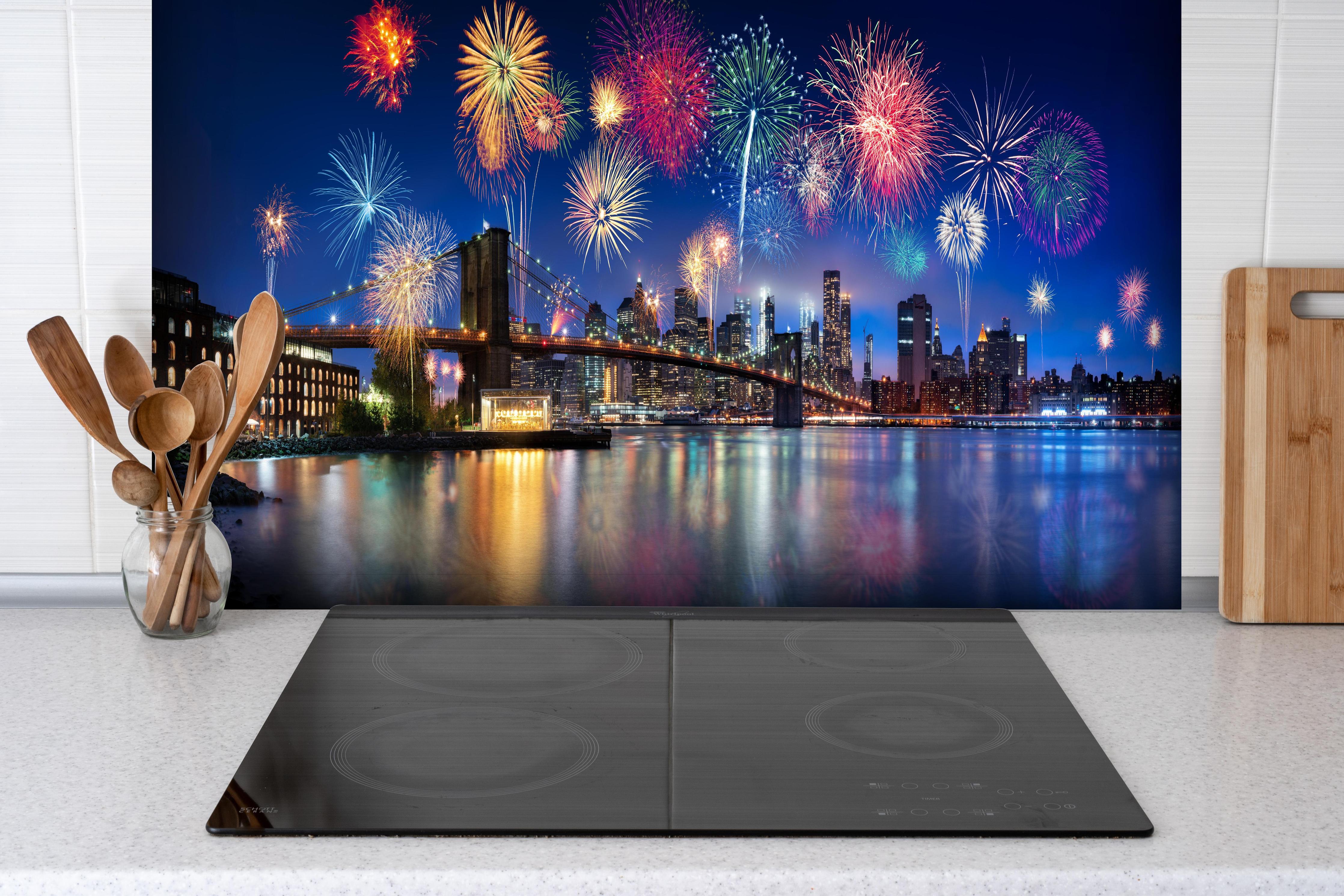 Spritzschutz - Feuerwerk über New York City hinter einem Cerankochfeld zwischen Holz-Kochutensilien

