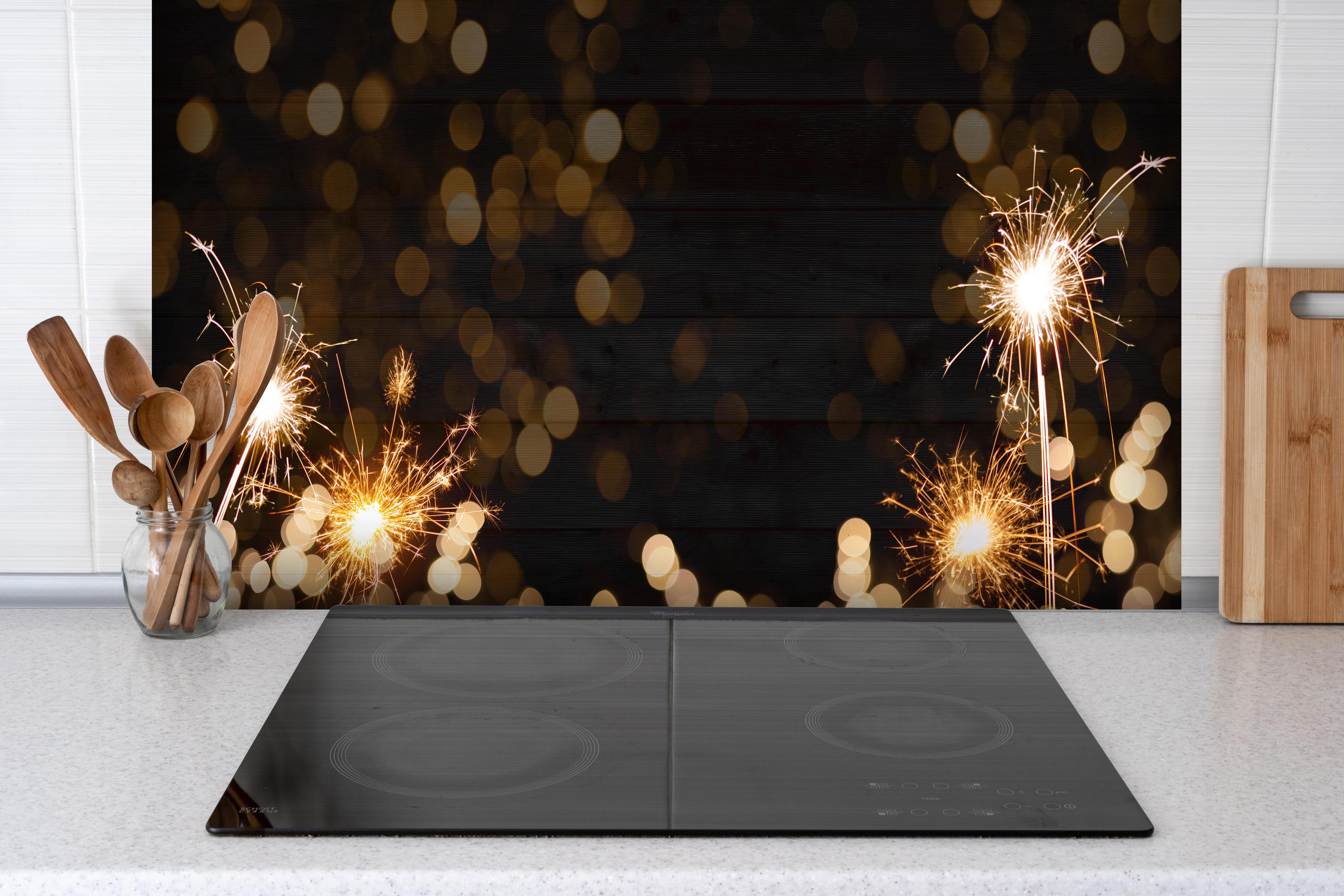 Spritzschutz - Feuerwerk und Sparkler Silvester Banner hinter einem Cerankochfeld zwischen Holz-Kochutensilien
