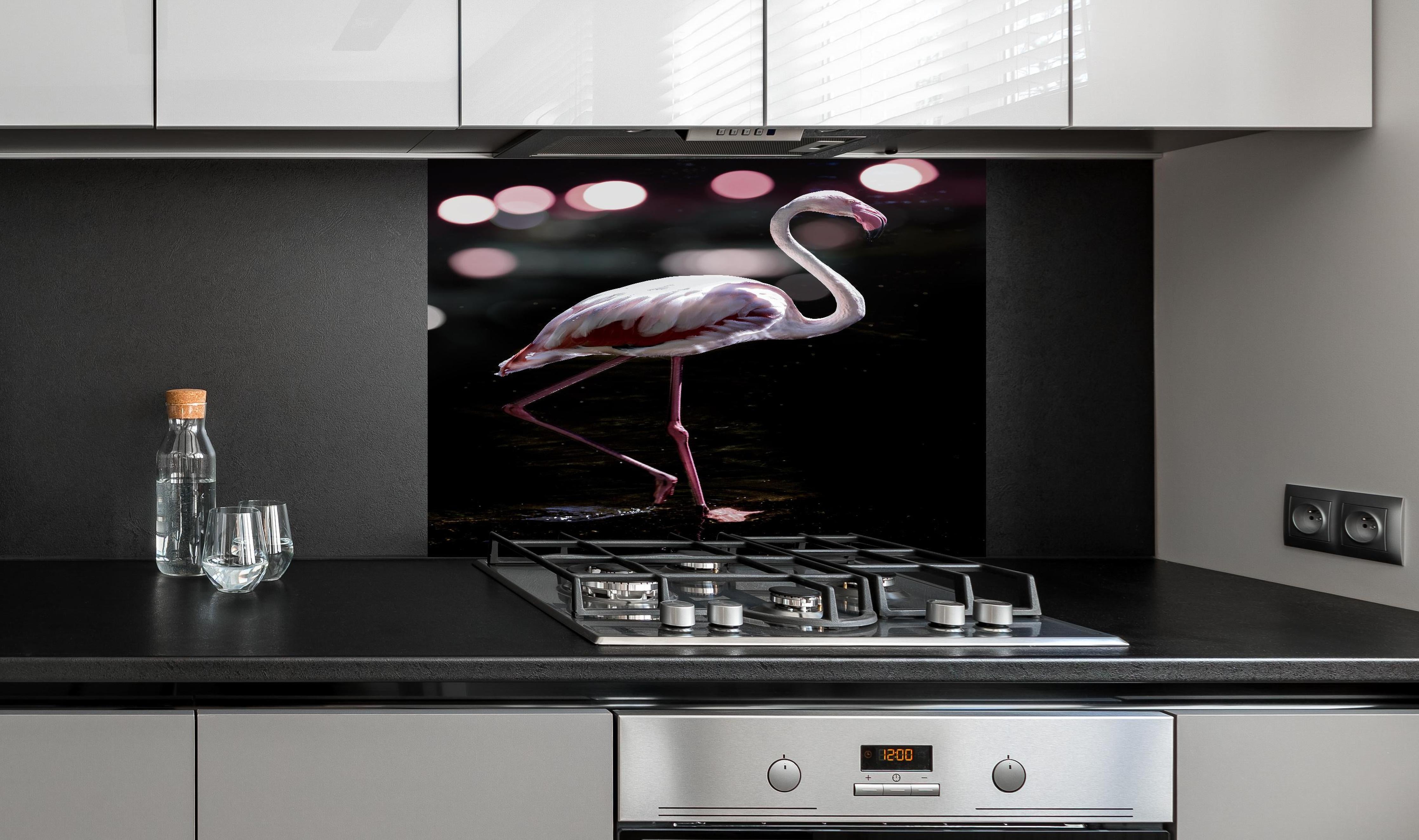Spritzschutz - Flamingo  hinter einem Cerankochfeld zwischen Holz-Kochutensilien

