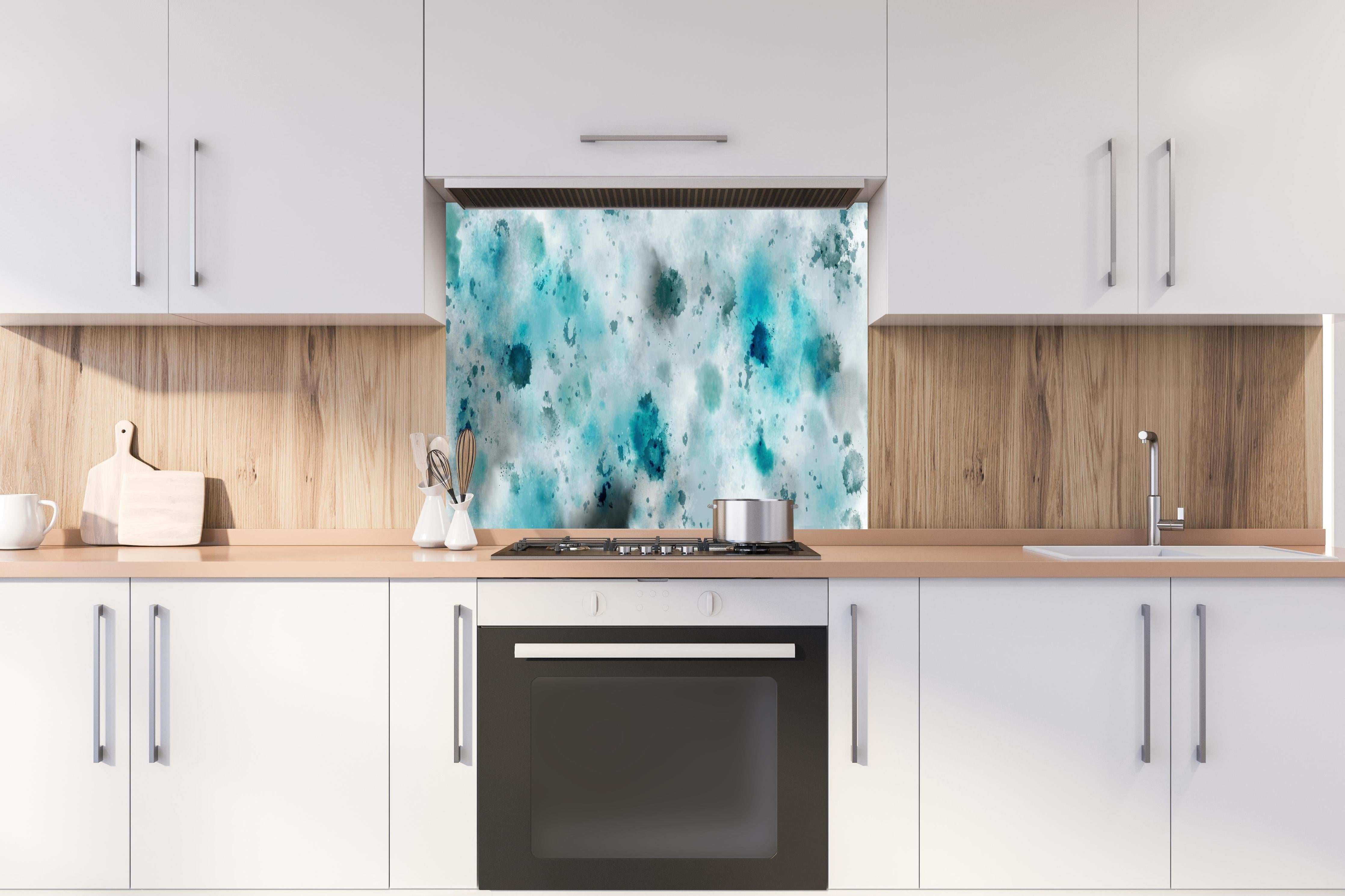 Spritzschutz - Flecken auf türkisfarbenen Aquarellhintergrund hinter einem Cerankochfeld zwischen Holz-Kochutensilien
