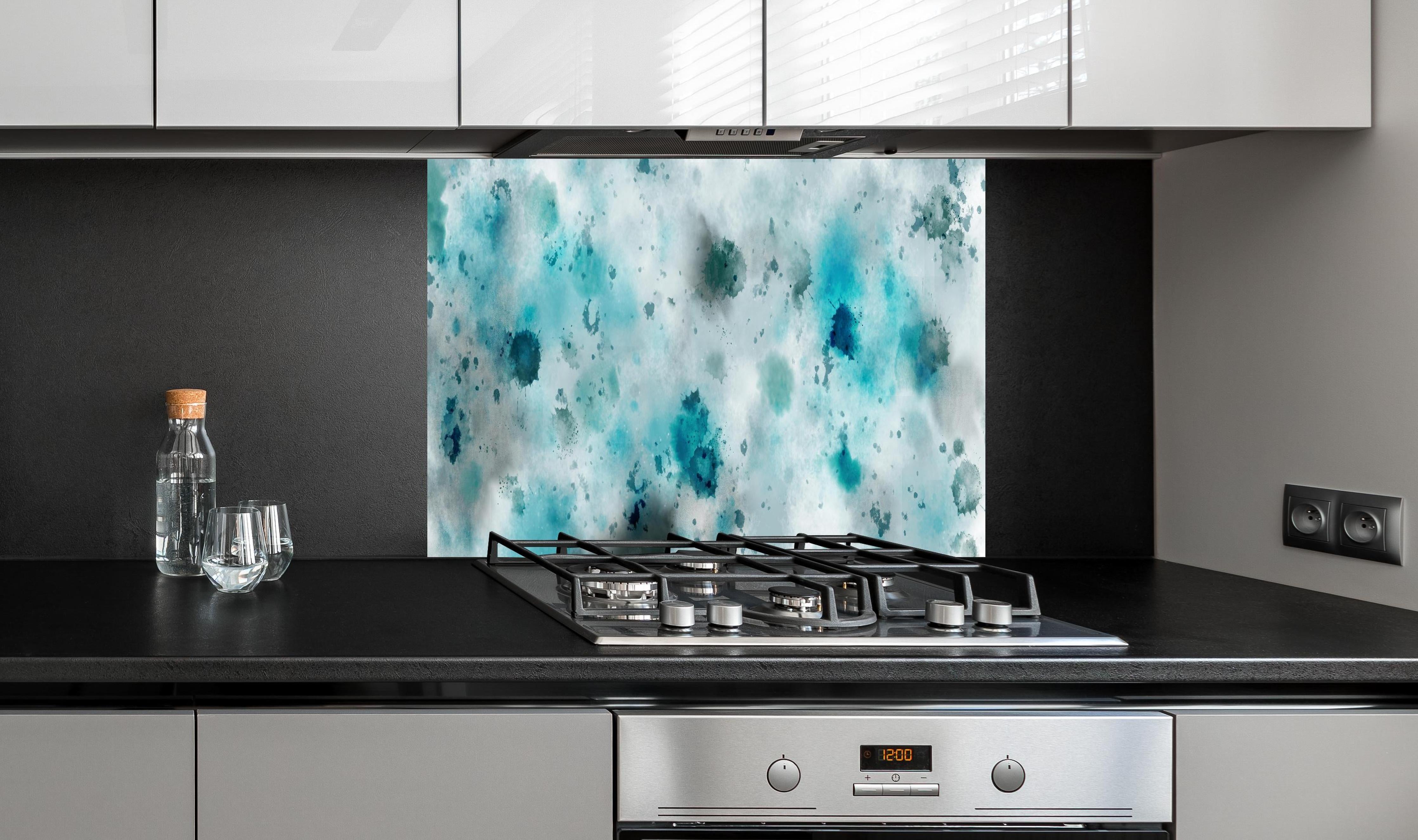 Spritzschutz - Flecken auf türkisfarbenen Aquarellhintergrund hinter einem Cerankochfeld zwischen Holz-Kochutensilien
