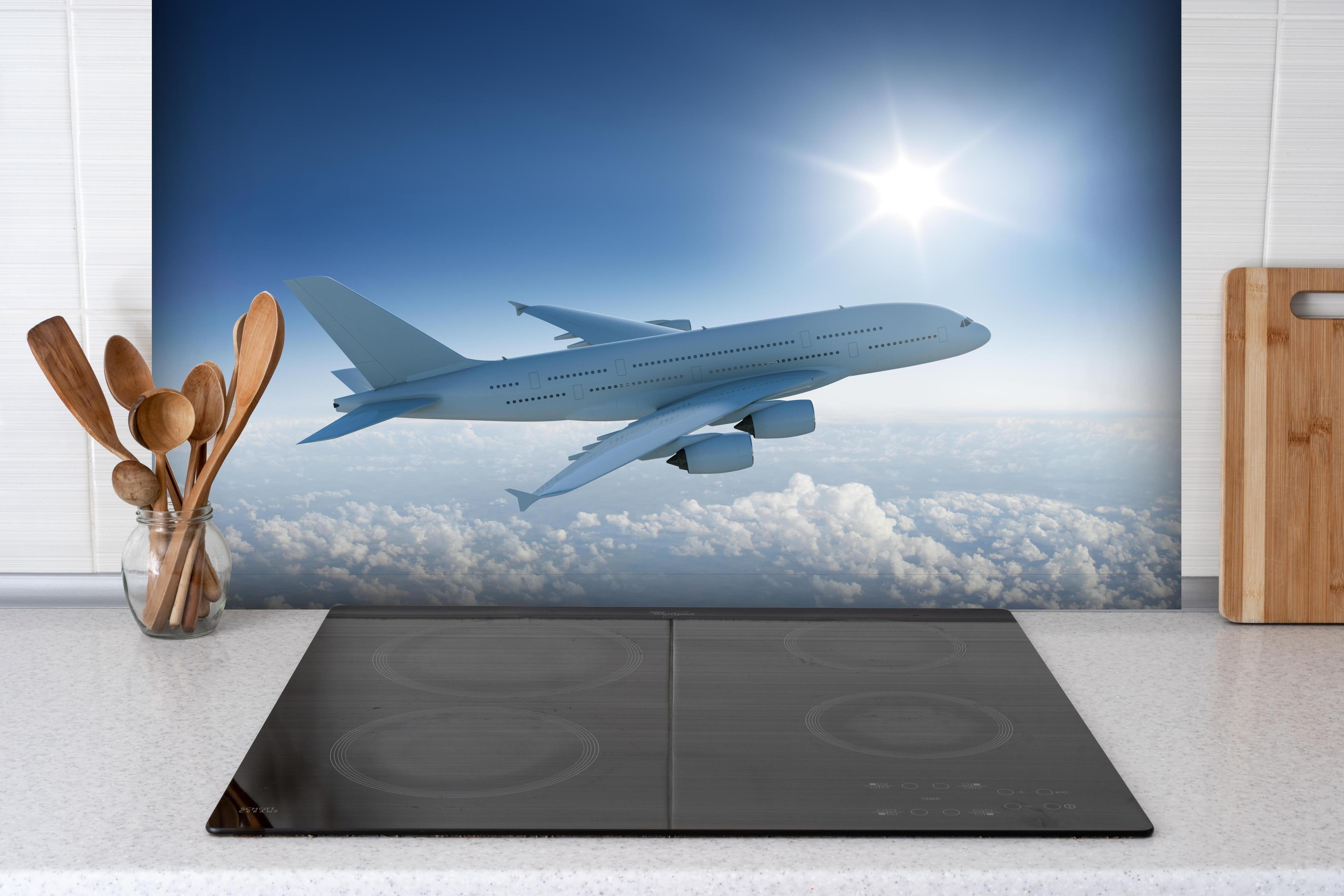 Spritzschutz - Flugzeug über weißen Wolken hinter einem Cerankochfeld zwischen Holz-Kochutensilien
