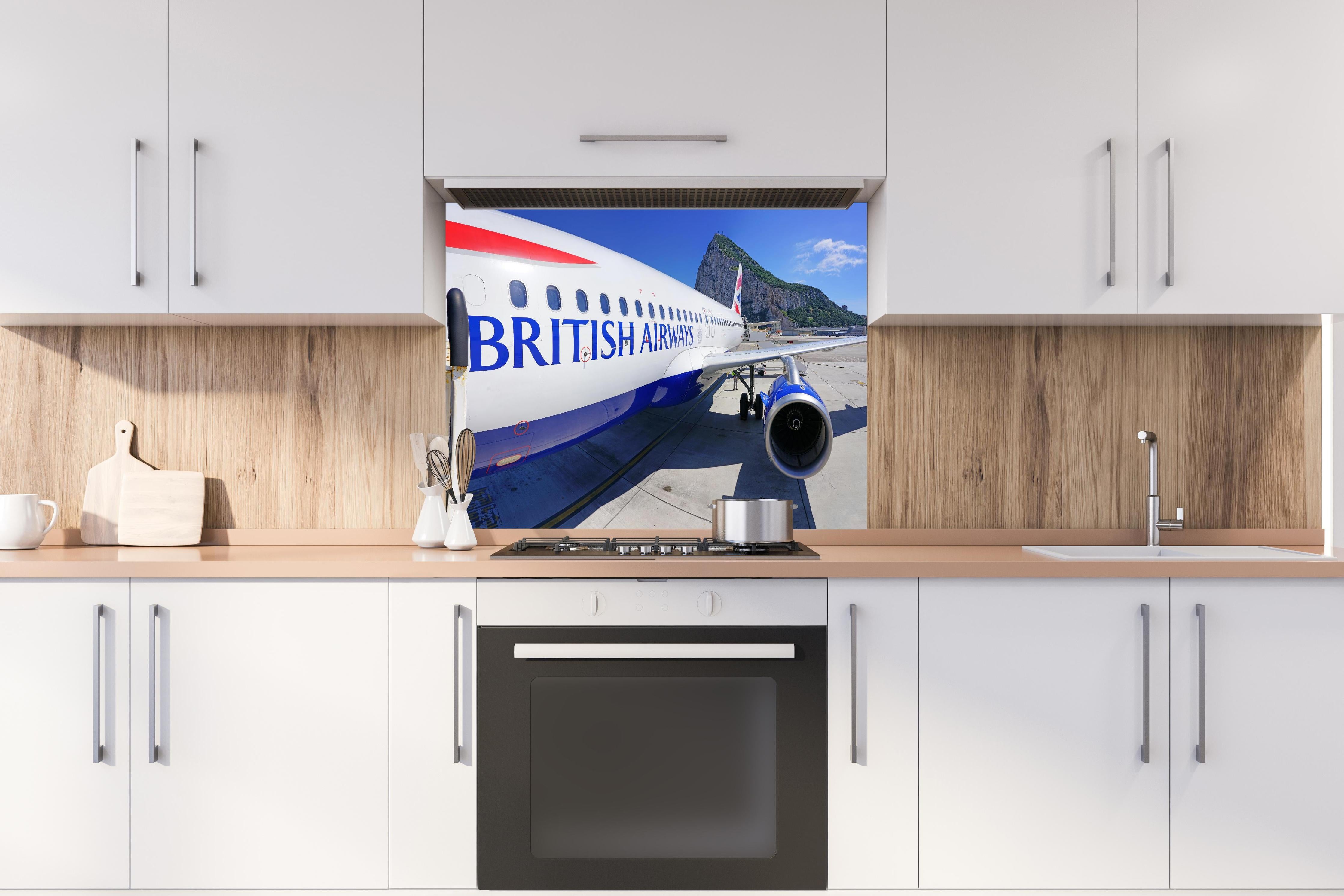 Spritzschutz - Flugzeug von British Airways hinter einem Cerankochfeld zwischen Holz-Kochutensilien
