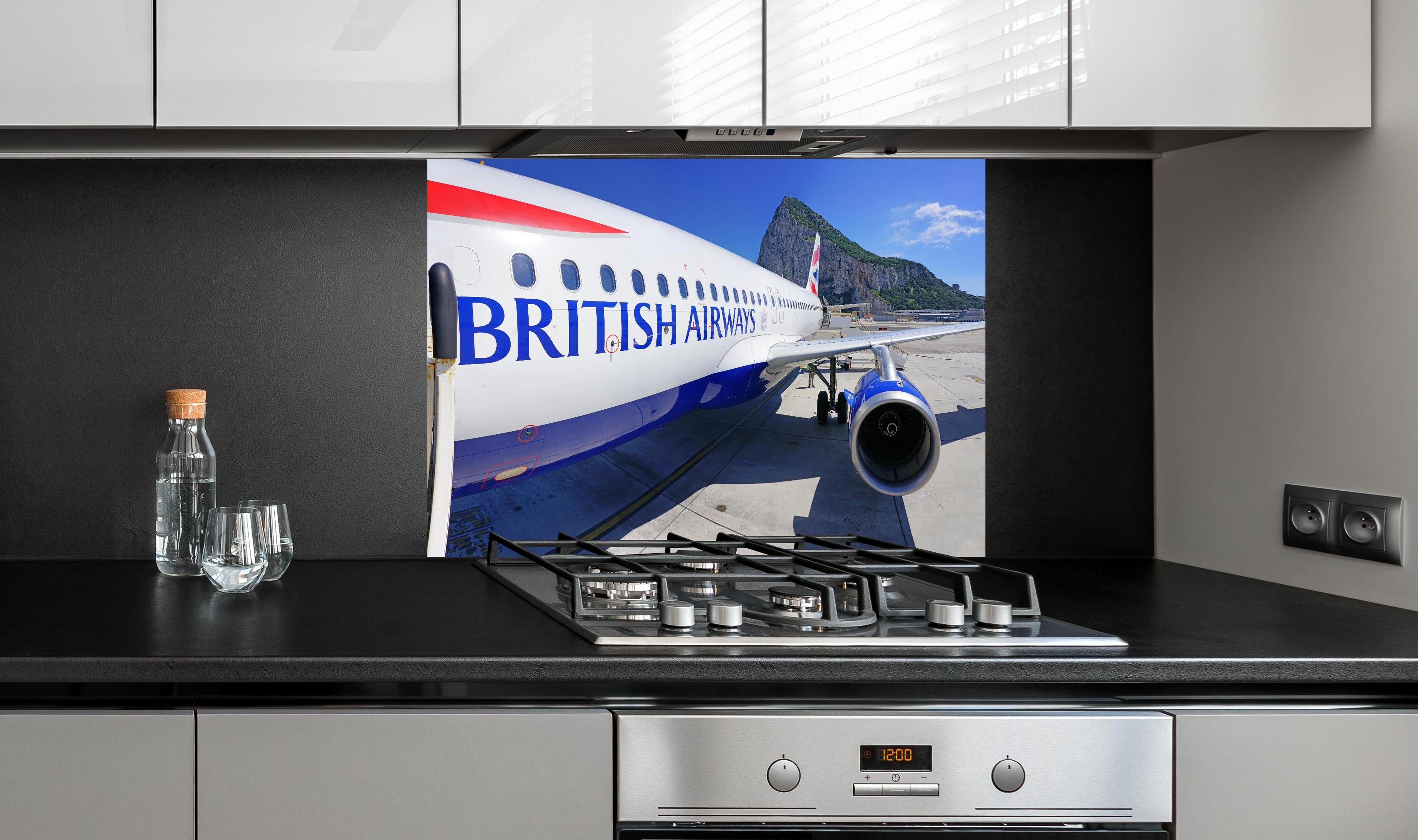 Spritzschutz - Flugzeug von British Airways hinter einem Cerankochfeld zwischen Holz-Kochutensilien
