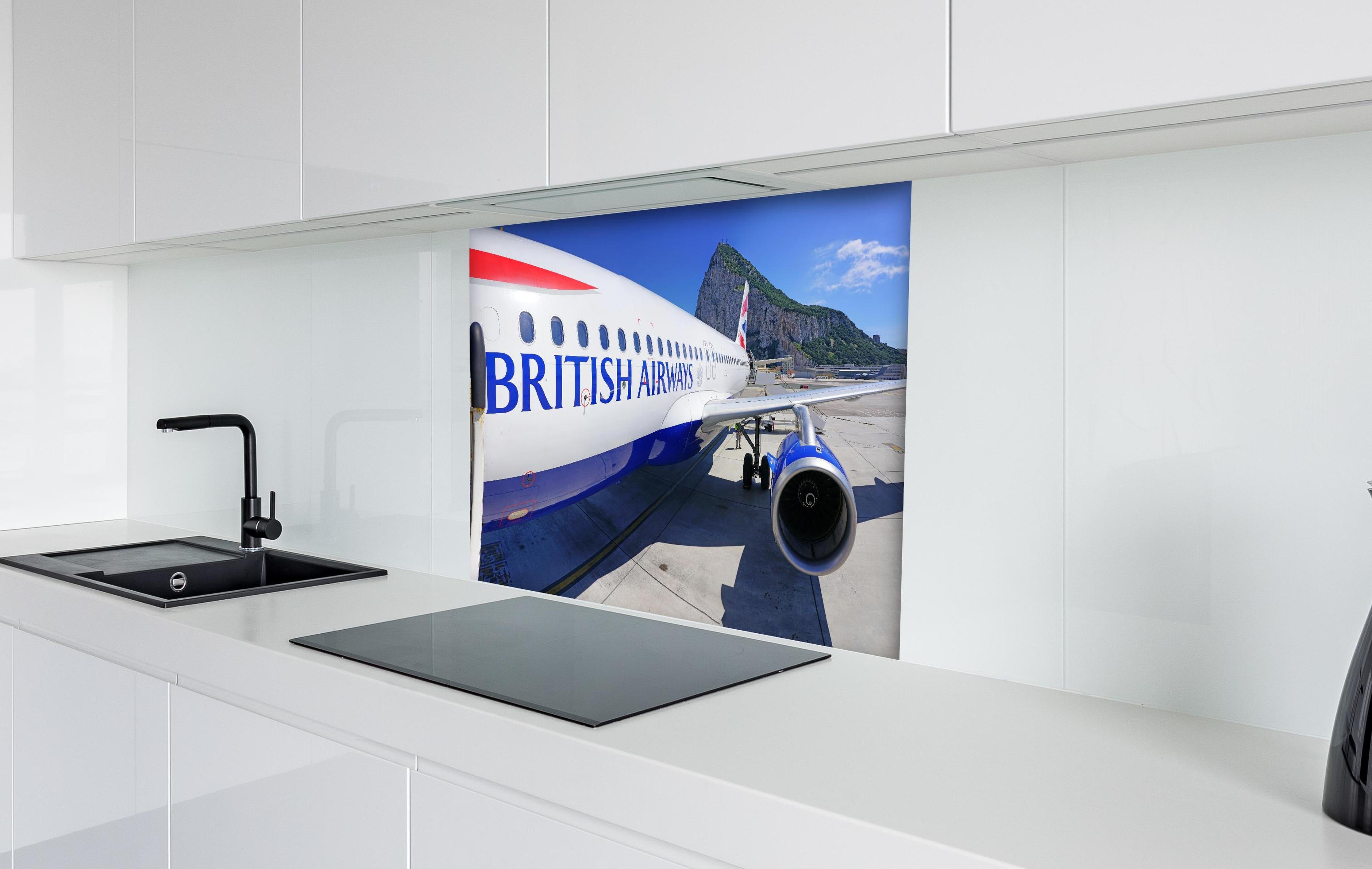 Spritzschutz - Flugzeug von British Airways hinter einem Cerankochfeld zwischen Holz-Kochutensilien
