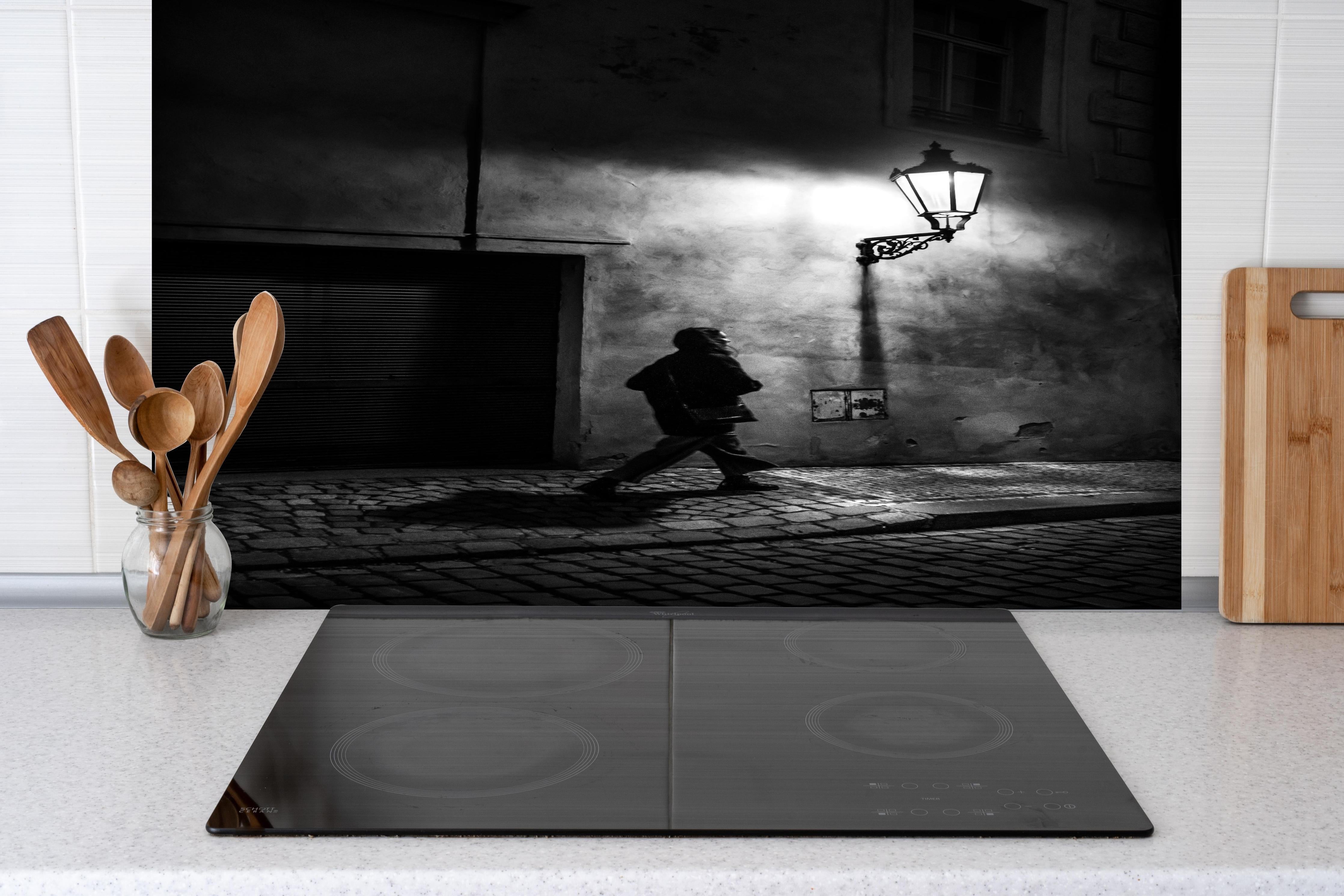 Spritzschutz - Frau im urbanen Nachtschatten Schwarz-Weiß hinter einem Cerankochfeld zwischen Holz-Kochutensilien

