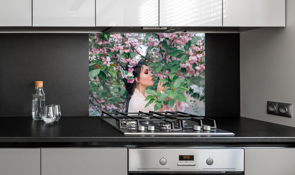 Spritzschutz - Frau in Kimono genießt Sakura-Garten hinter einem Cerankochfeld zwischen Holz-Kochutensilien
