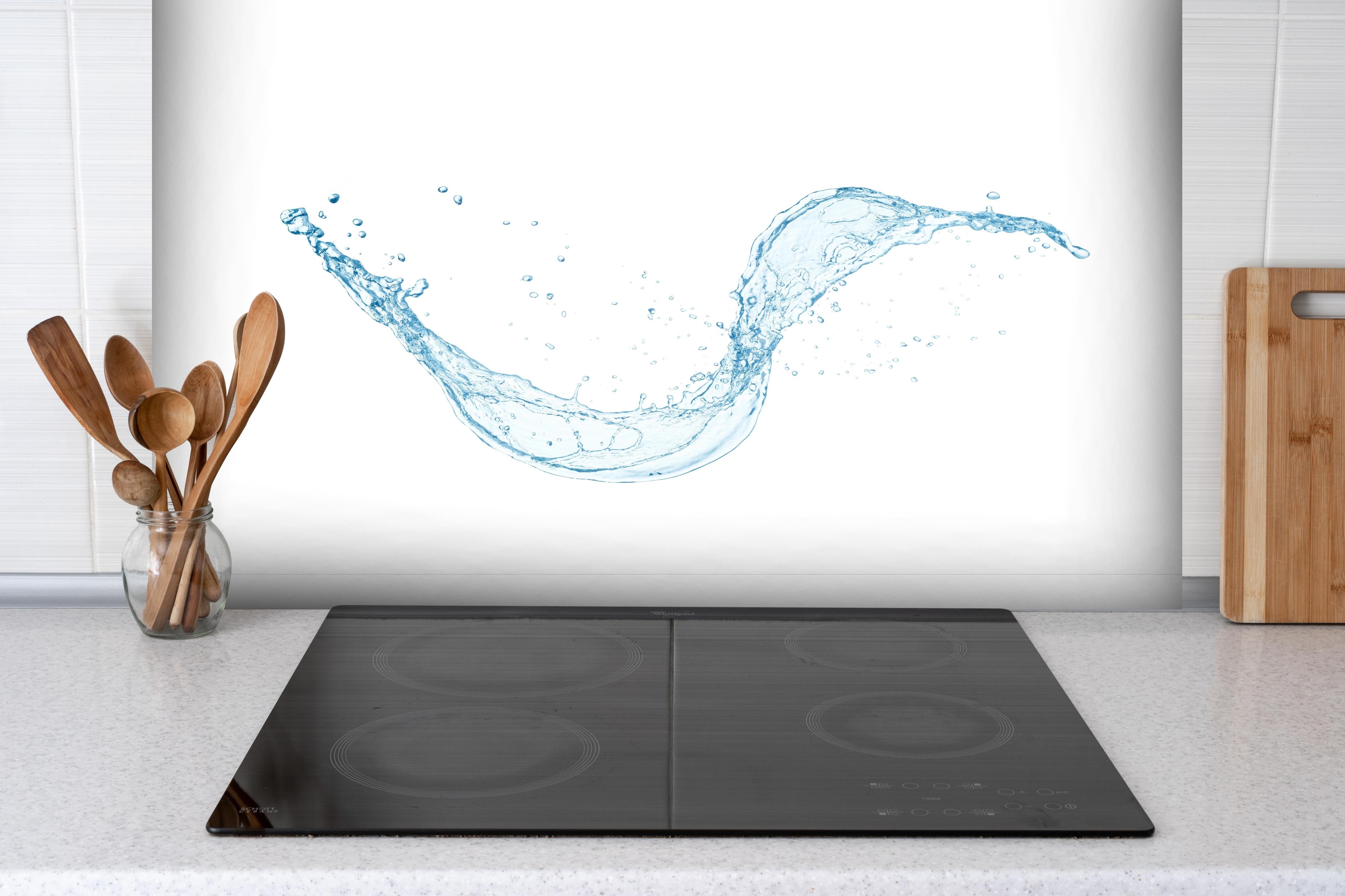 Spritzschutz - Frischer Blauer Wasser Splash Isoliert hinter einem Cerankochfeld zwischen Holz-Kochutensilien
