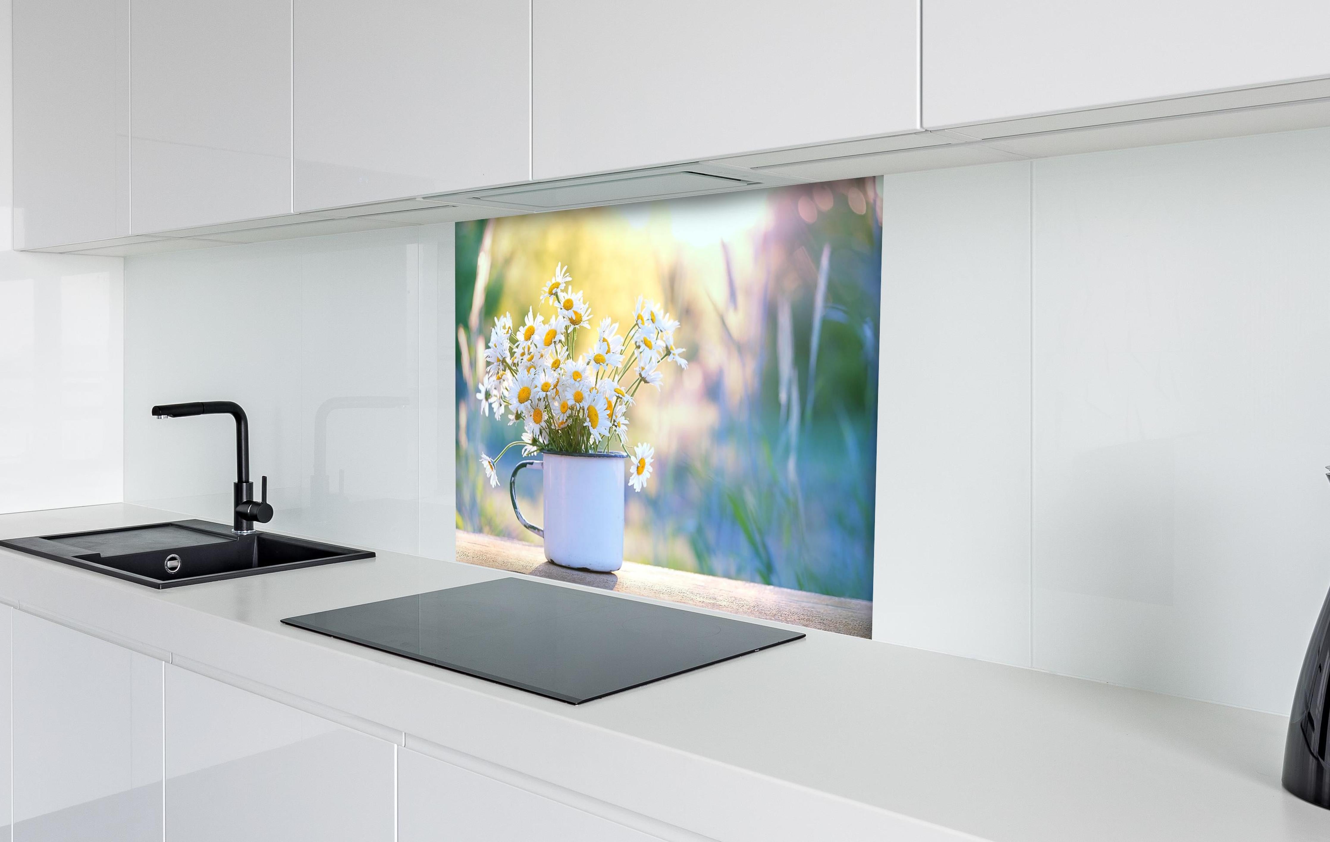 Spritzschutz - Gänseblümchen im Licht des Sonnenuntergangs hinter einem Cerankochfeld zwischen Holz-Kochutensilien
