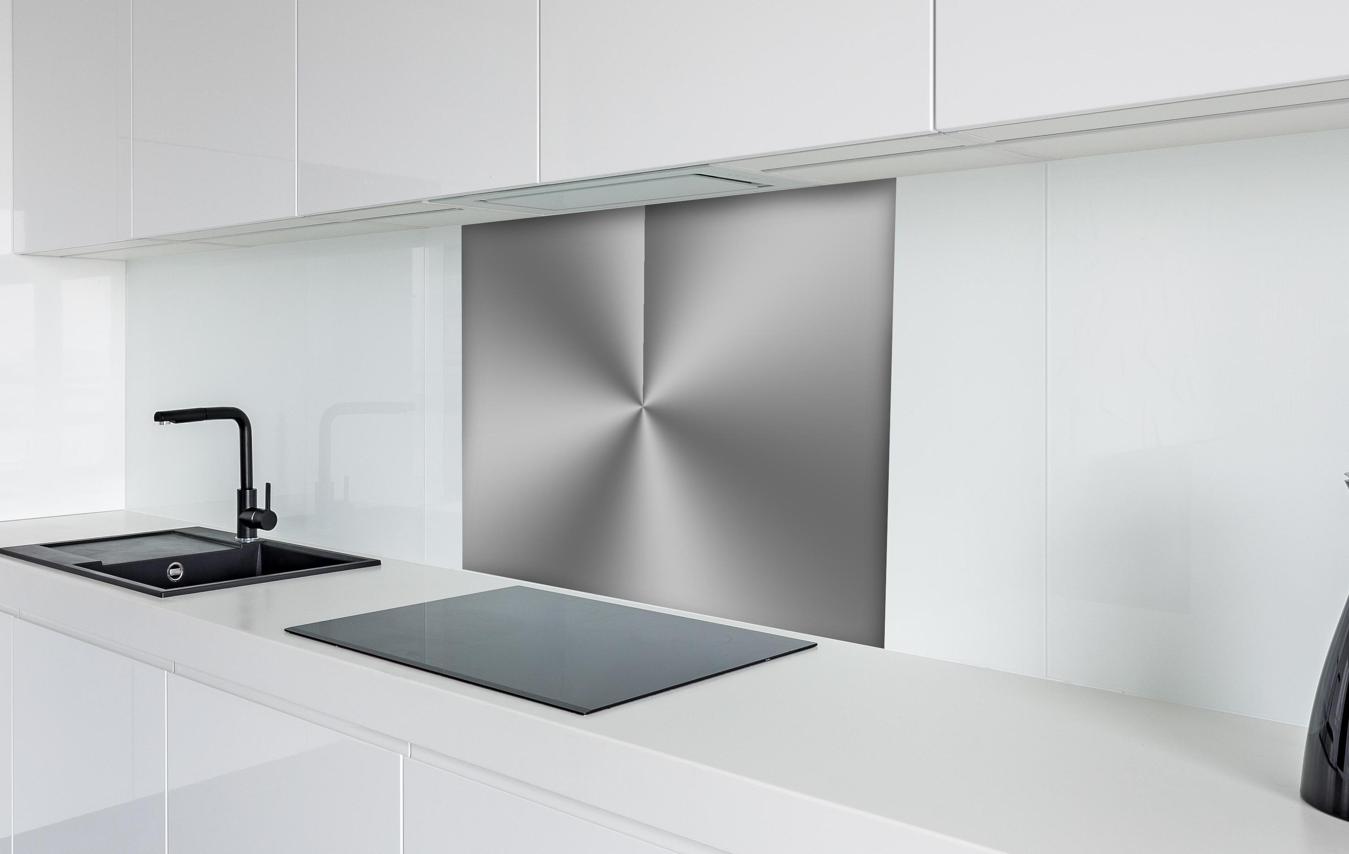 Spritzschutz - Gebürstetes Metall hinter einem Cerankochfeld zwischen Holz-Kochutensilien
